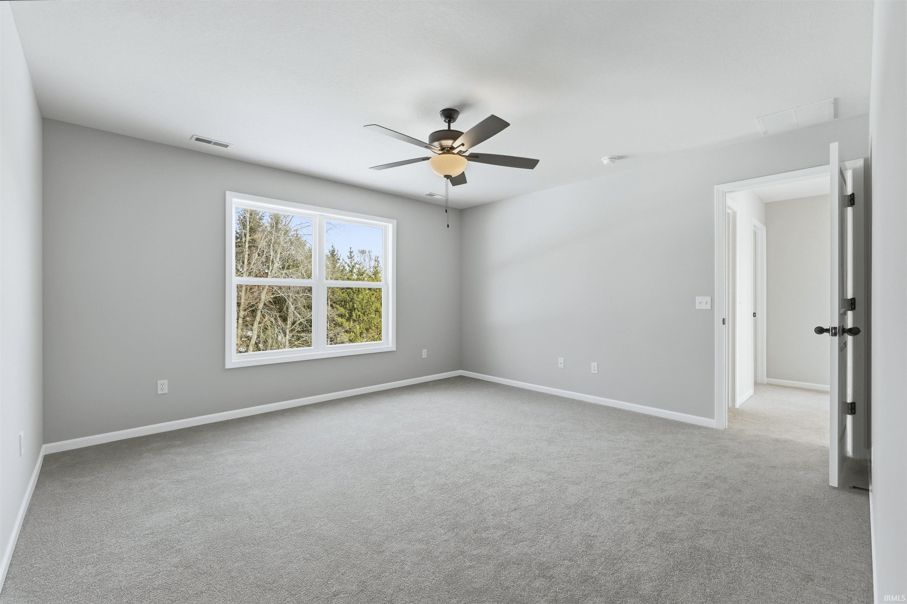 Spare room featuring a ceiling fan and light colored carpet