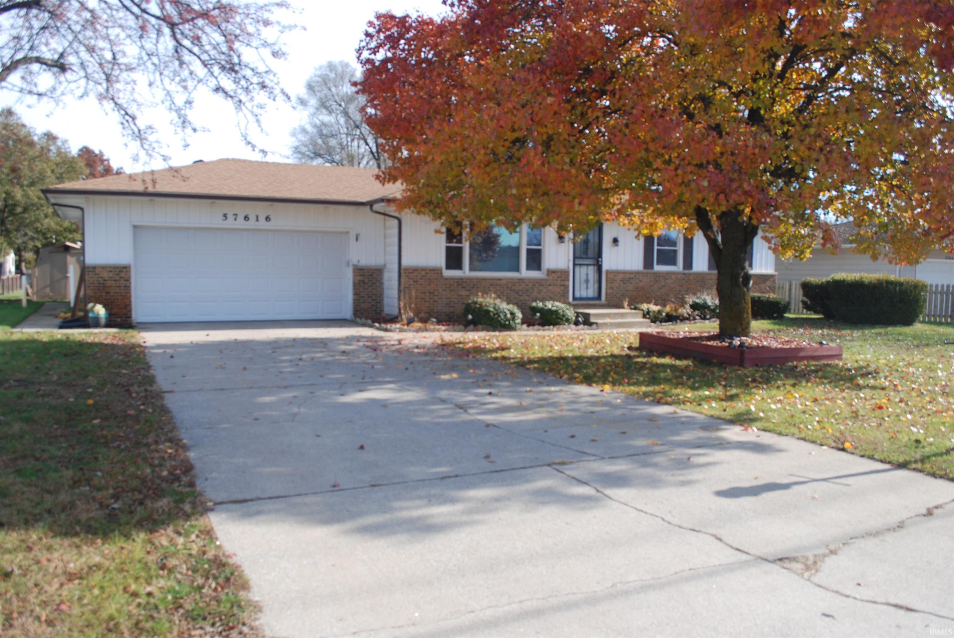 View of front of house with brick siding, driveway, an attached garage, and a front yard