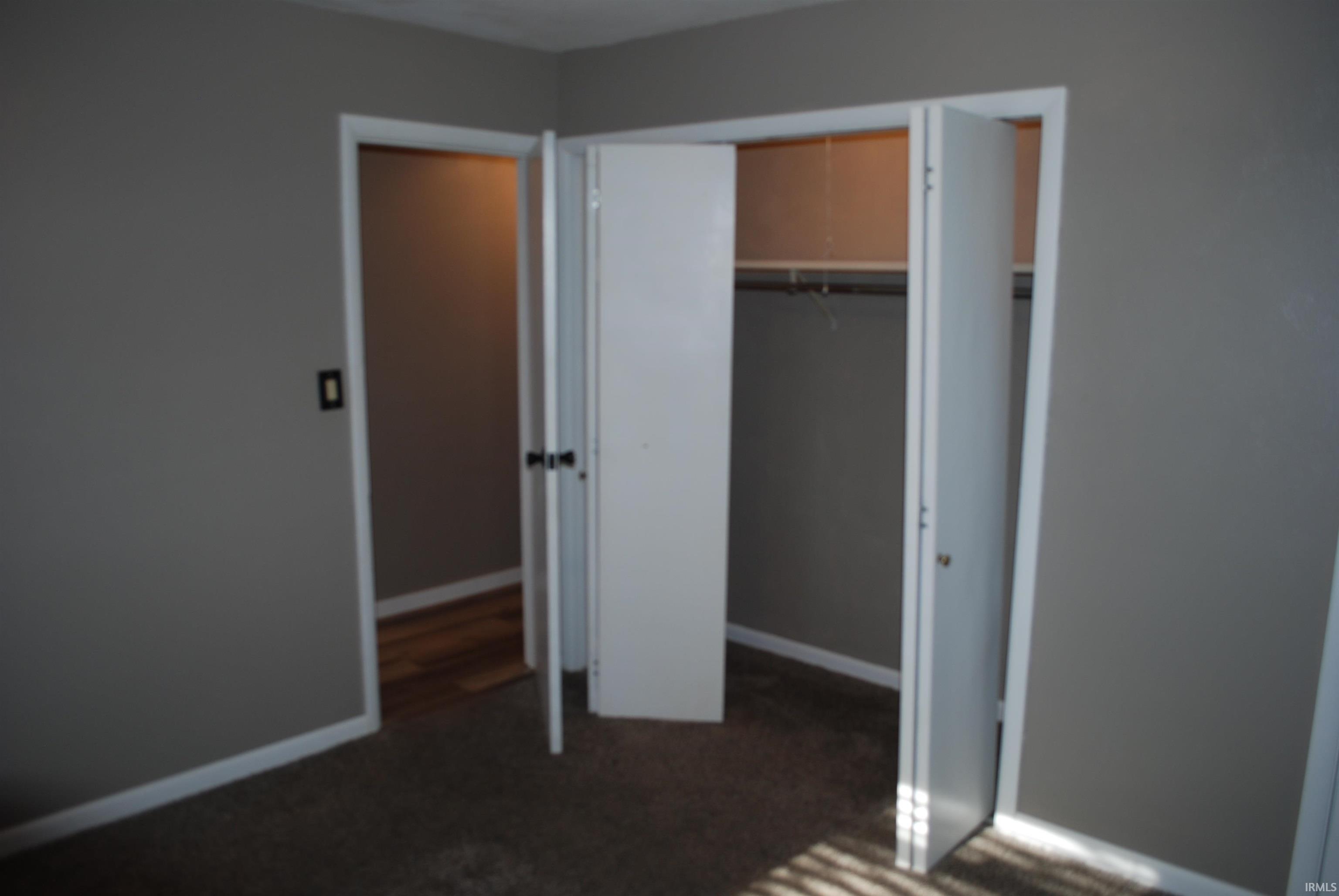 Unfurnished bedroom with dark colored carpet and a closet