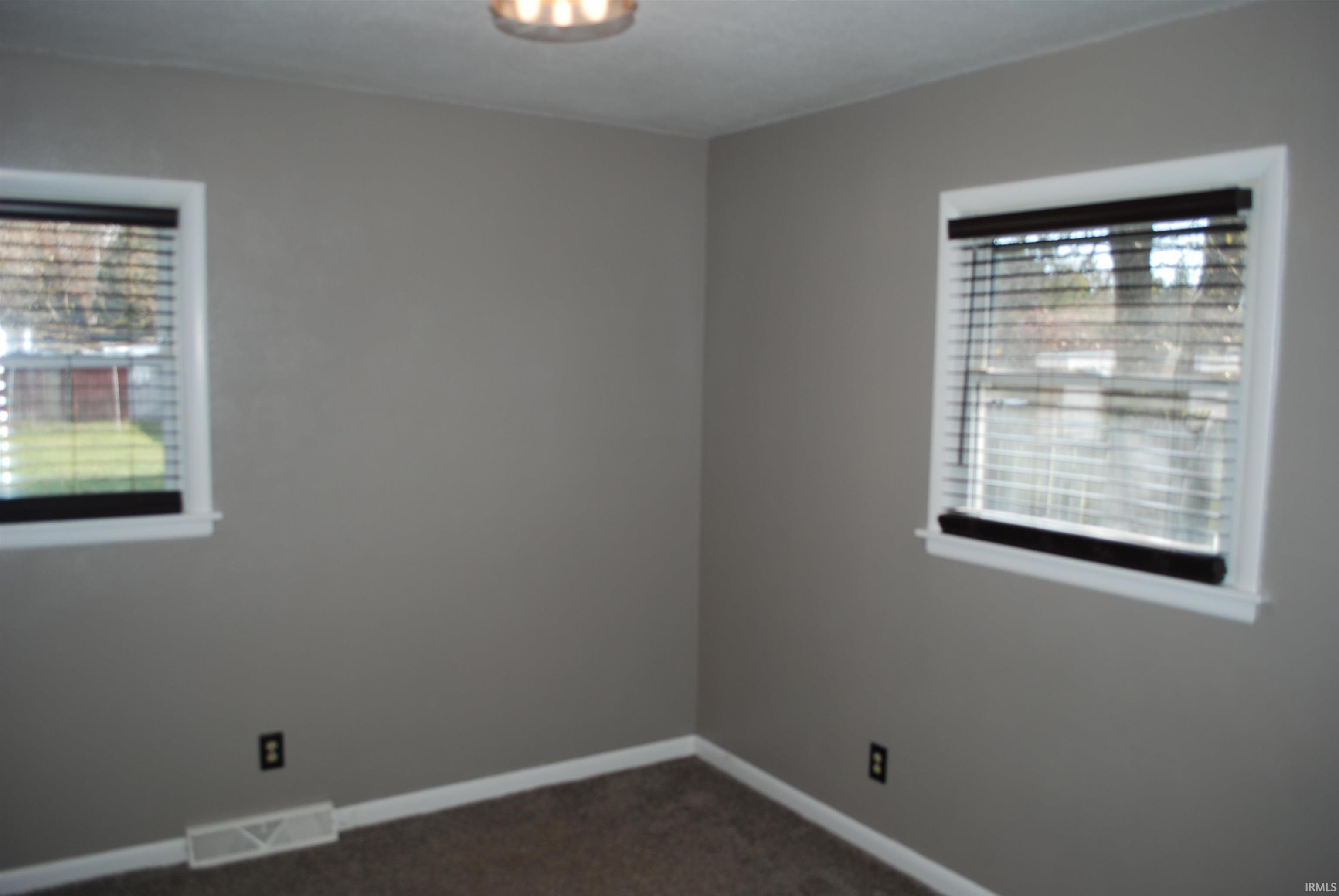 Spare room featuring healthy amount of natural light and dark carpet