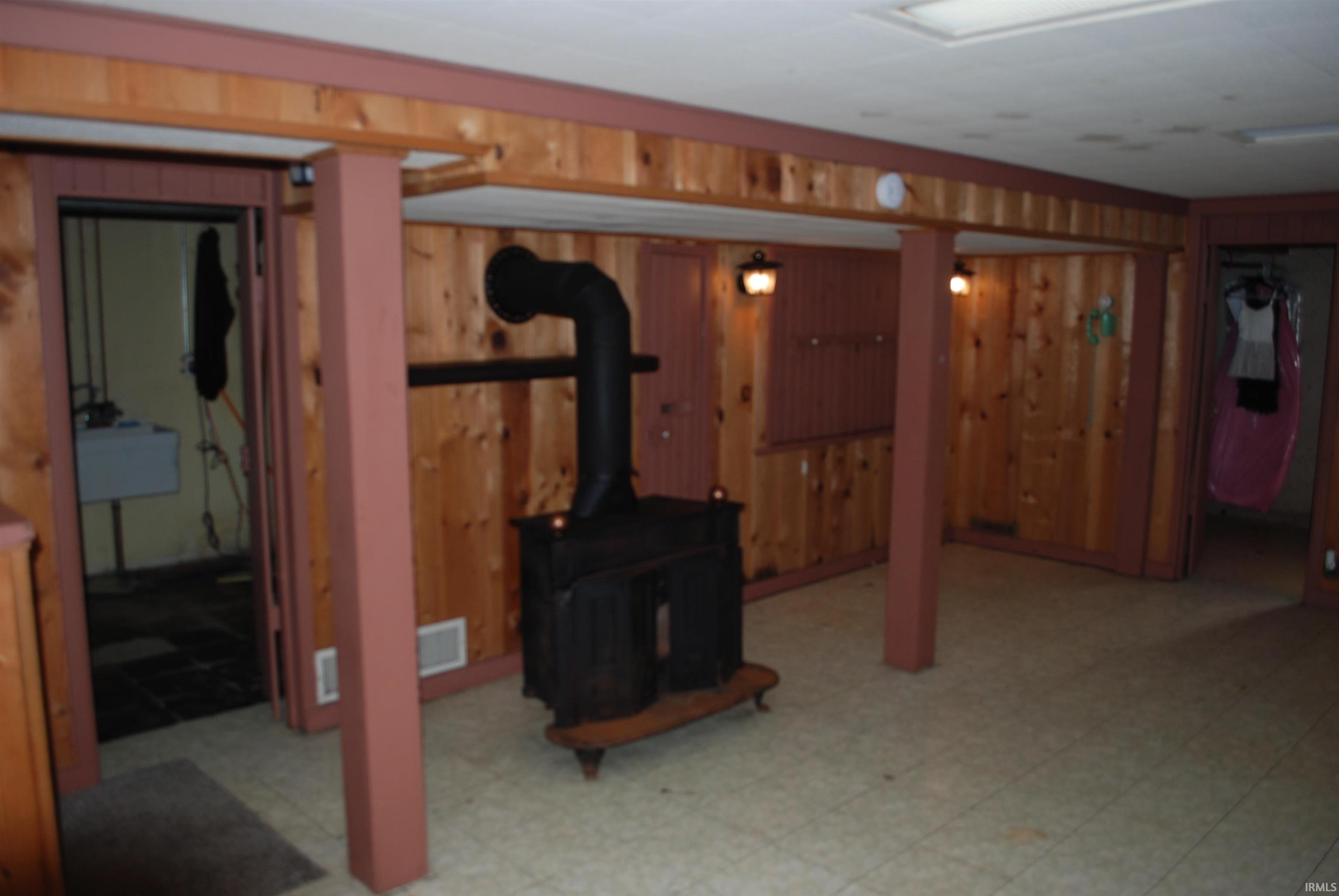 Finished below grade area with a wood stove, wood walls, and light flooring