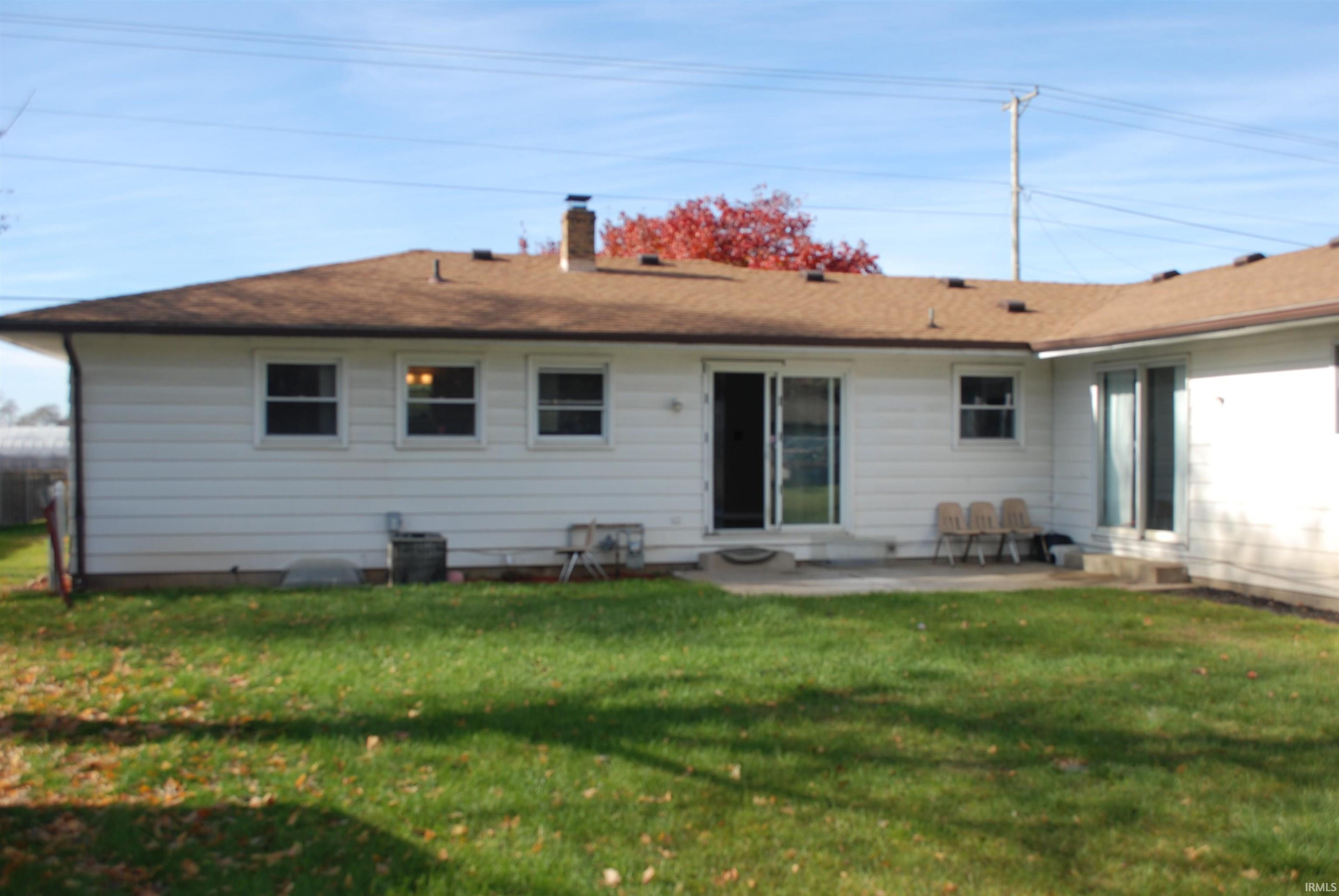 Back of house featuring a lawn, a patio area, and a chimney