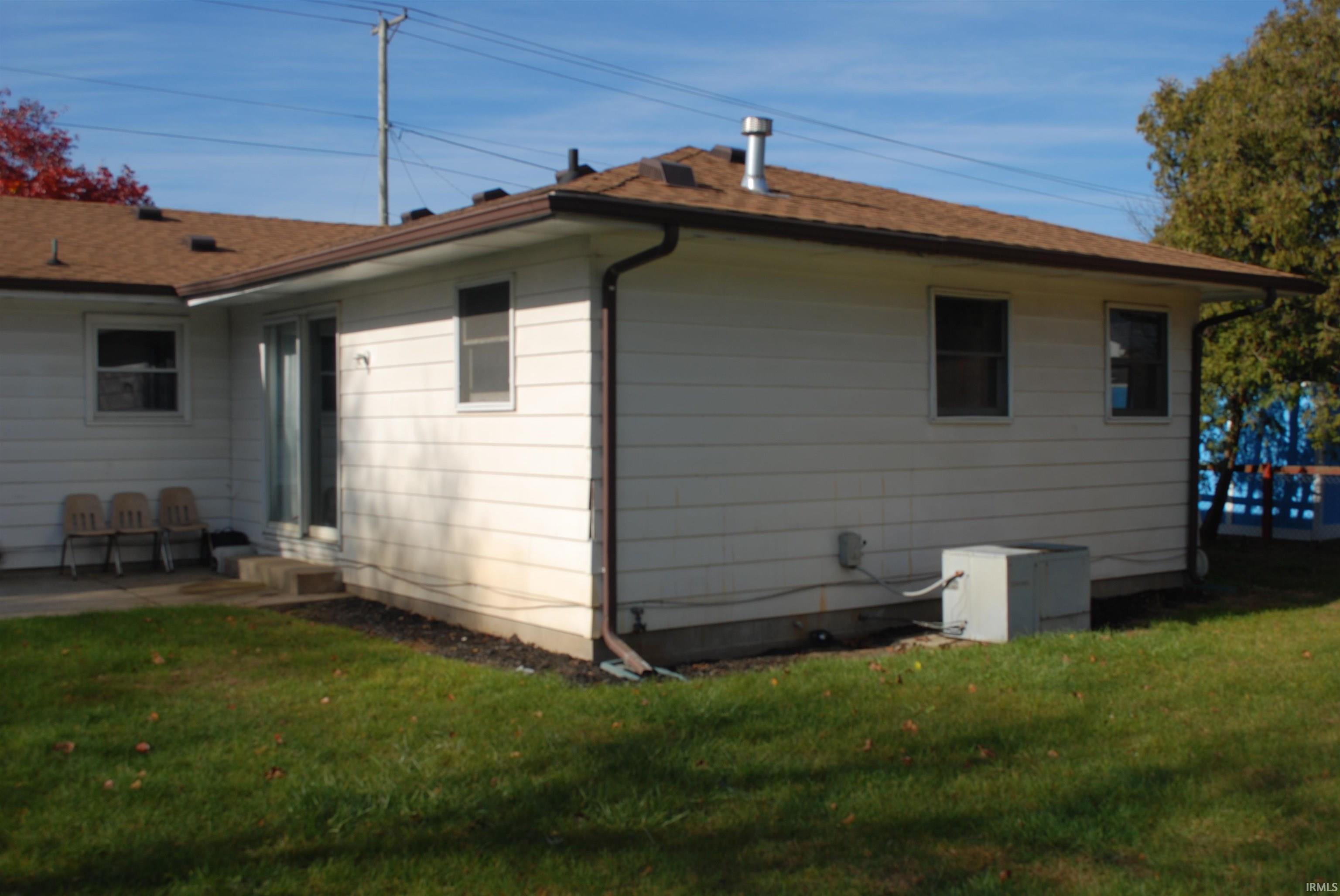 Back of property featuring a yard and roof with shingles