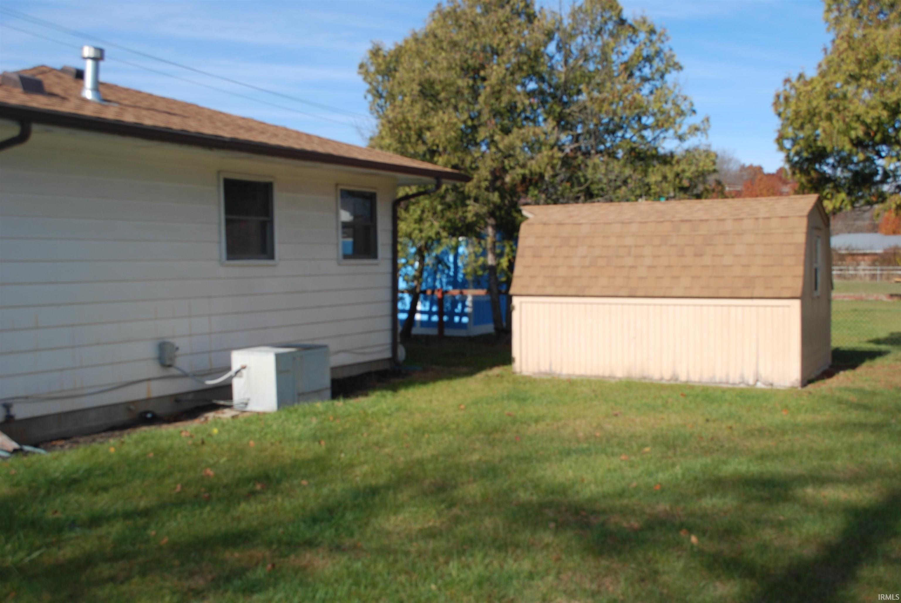 View of property exterior featuring a lawn and a storage unit
