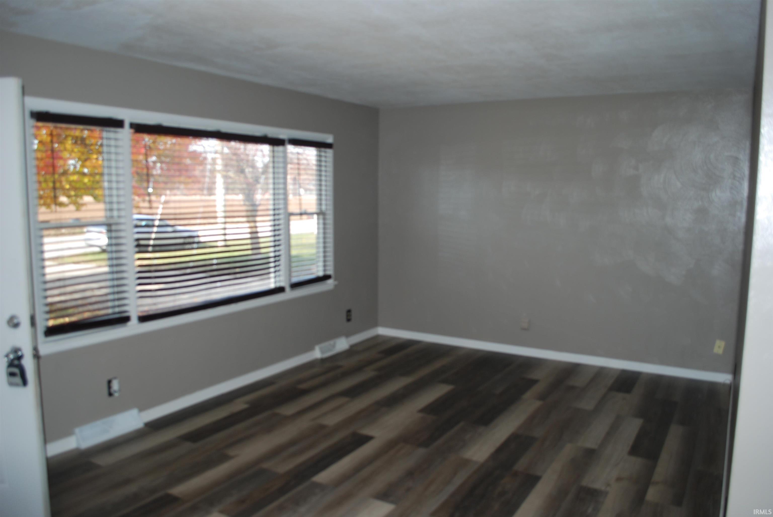 Unfurnished room featuring dark wood-style floors and baseboards
