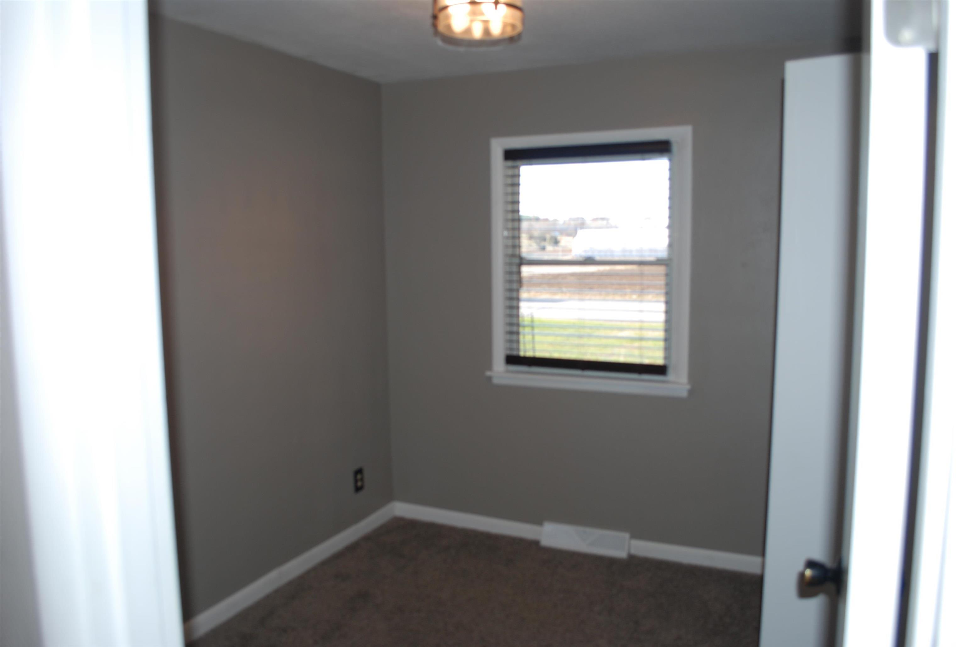 Empty room with dark carpet and baseboards