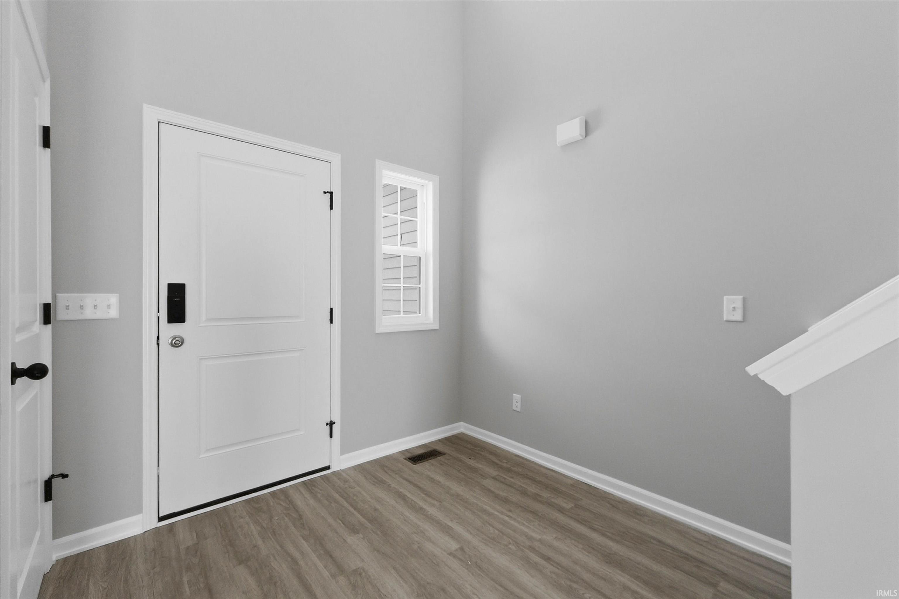 Foyer entrance with wood finished floors and a high ceiling