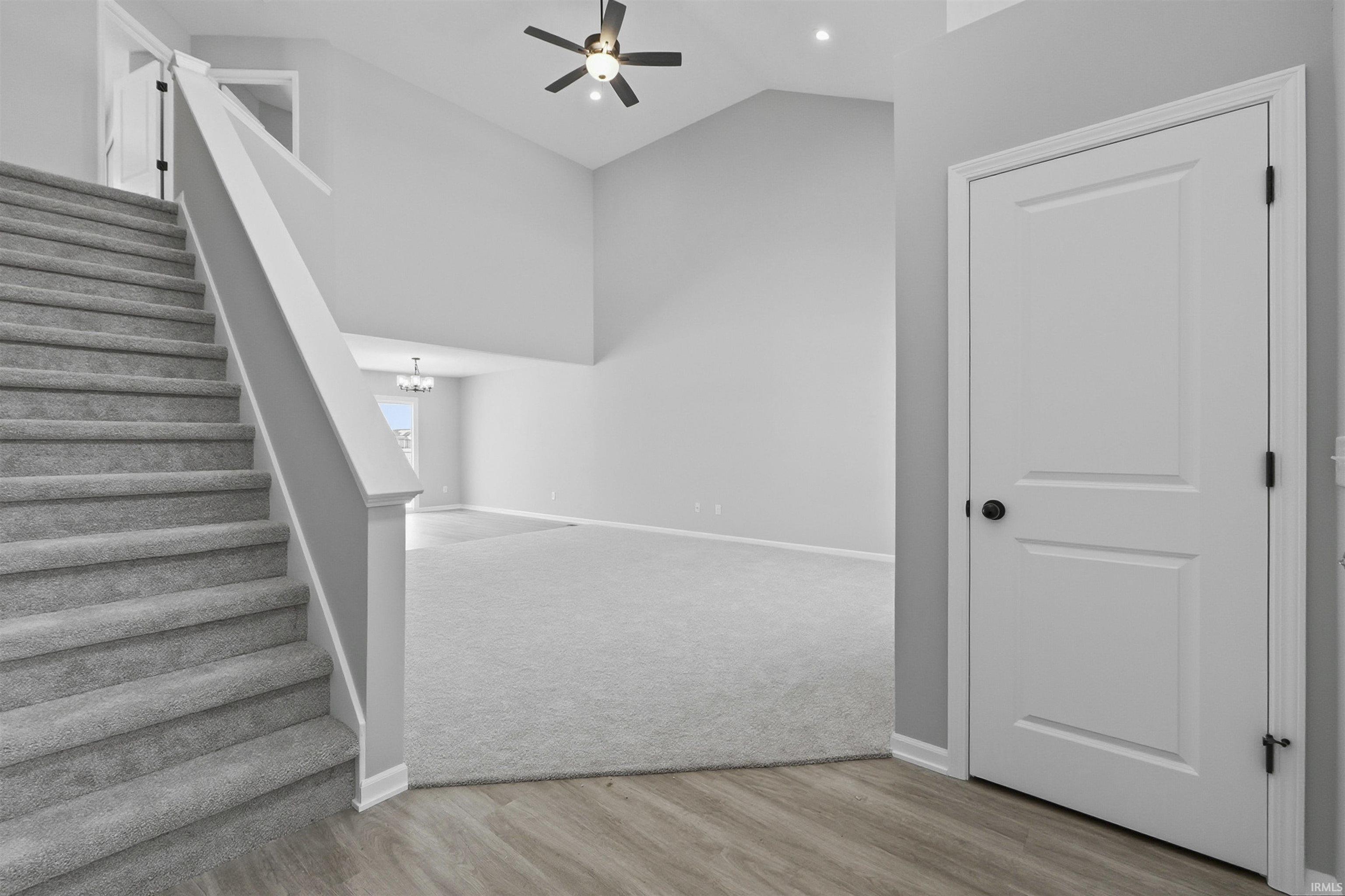Stairway featuring a high ceiling, wood finished floors, a ceiling fan, and suspended lighting