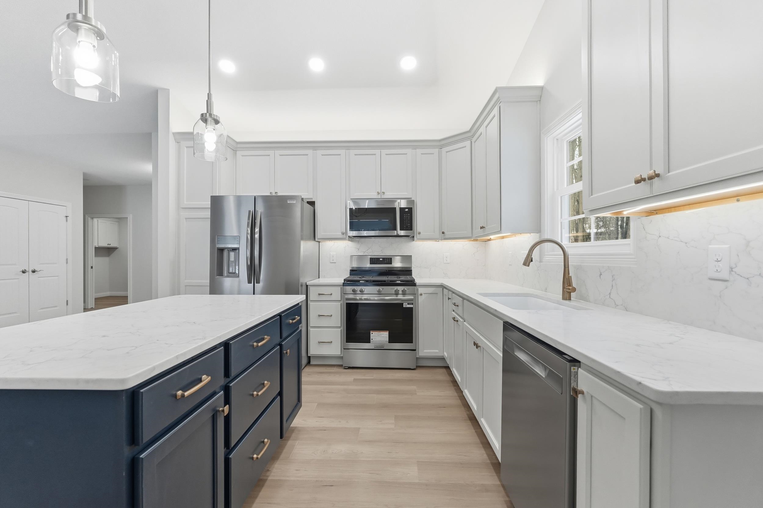 Kitchen featuring appliances with stainless steel finishes, light stone countertops, decorative light fixtures, recessed lighting, and a center island