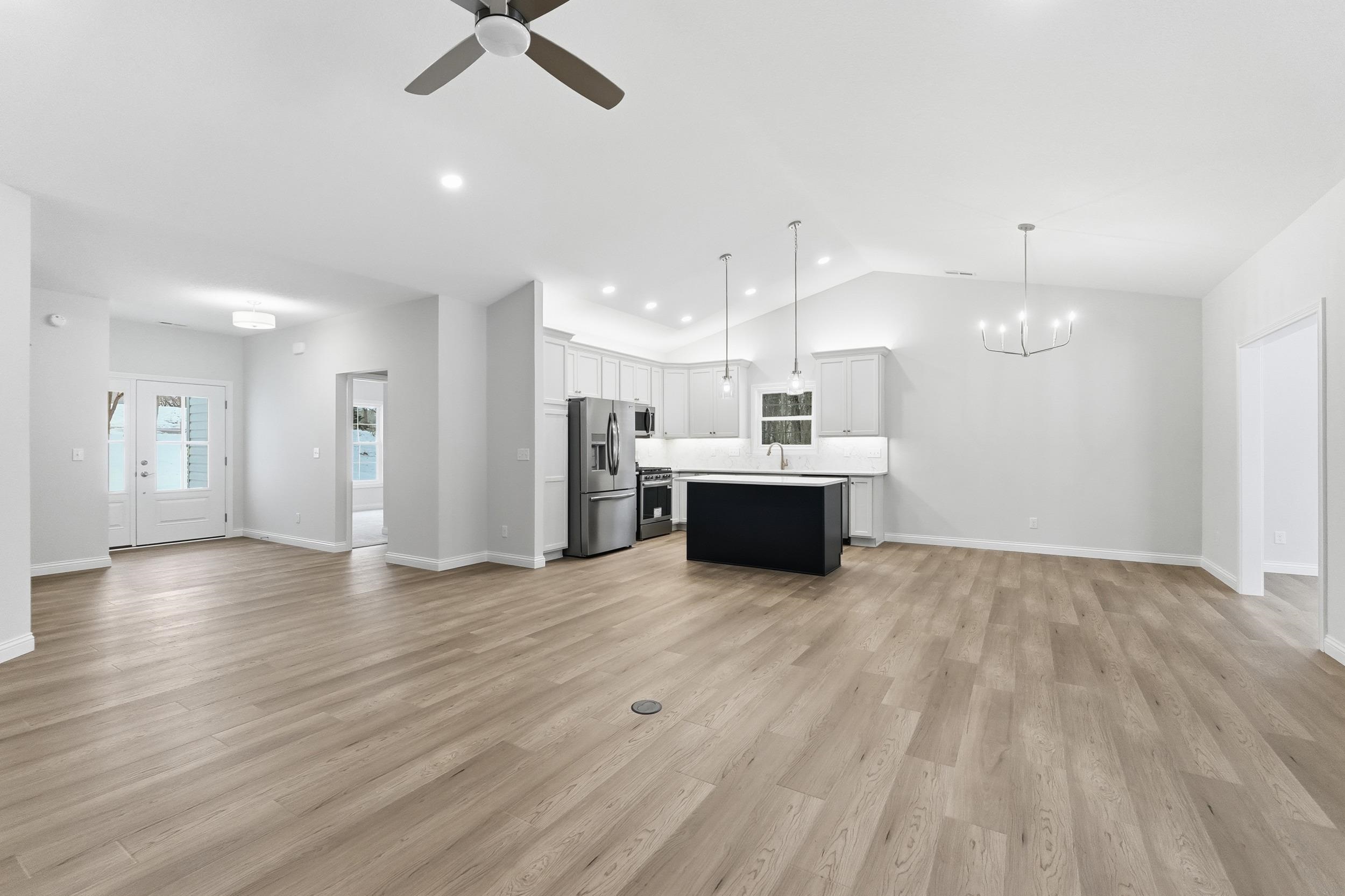 Kitchen with open floor plan, hanging light fixtures, white cabinetry, a kitchen island, and vaulted ceiling