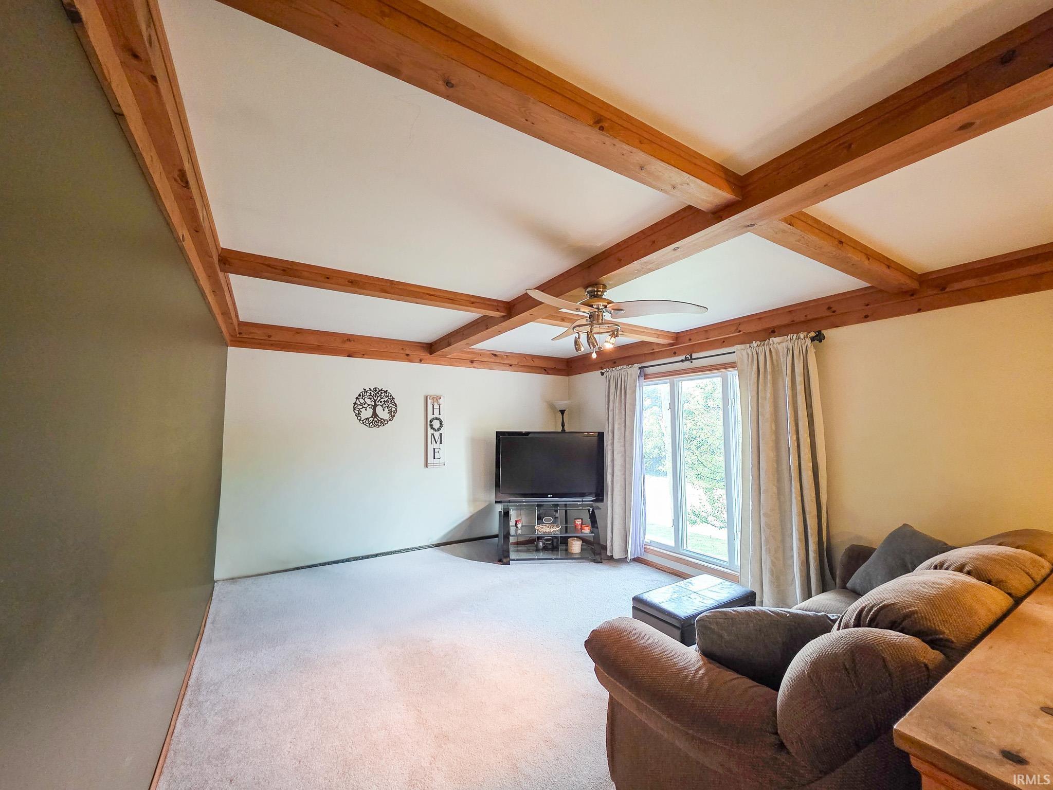 Living area with coffered ceiling, a ceiling fan, and carpet flooring