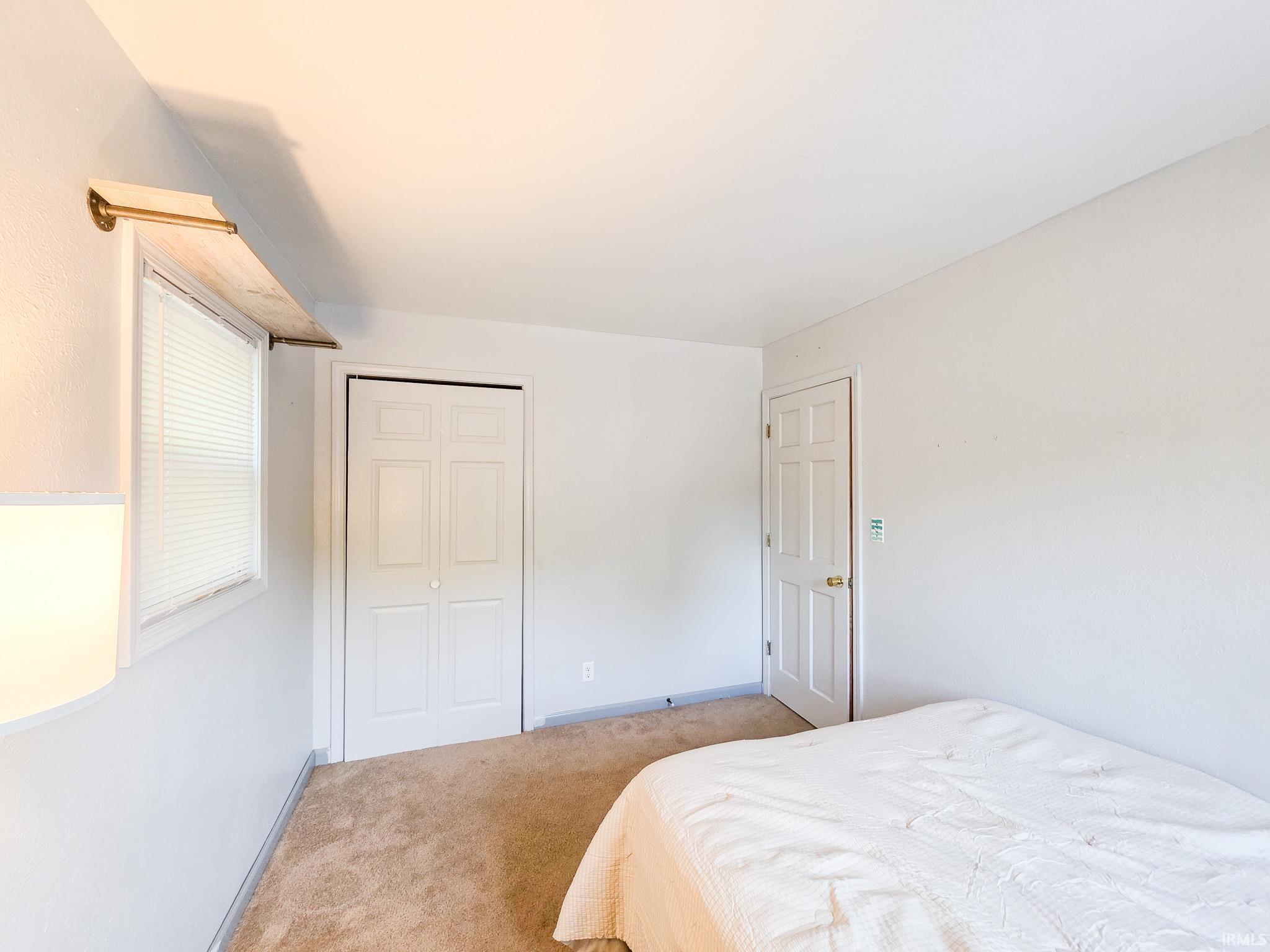 Bedroom with light colored carpet and a closet