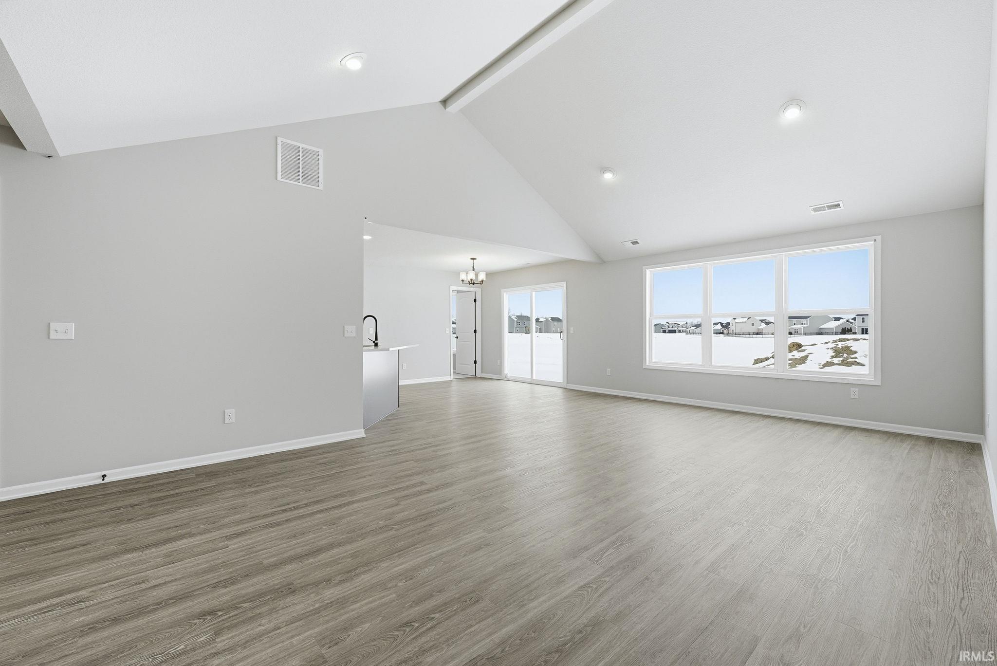 Unfurnished living room with dark wood-type flooring and a chandelier