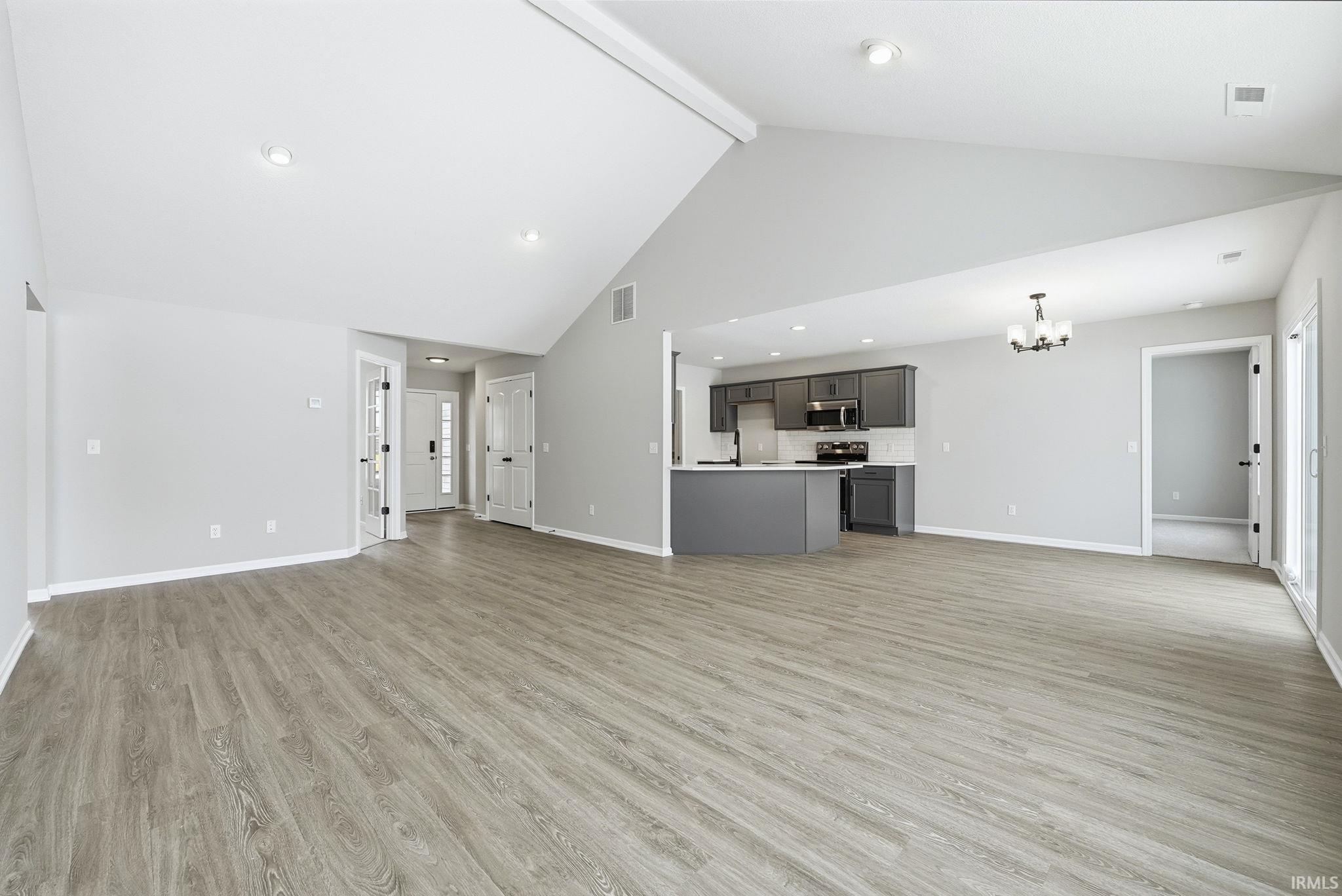 Unfurnished living room with suspended lighting and light wood-style flooring