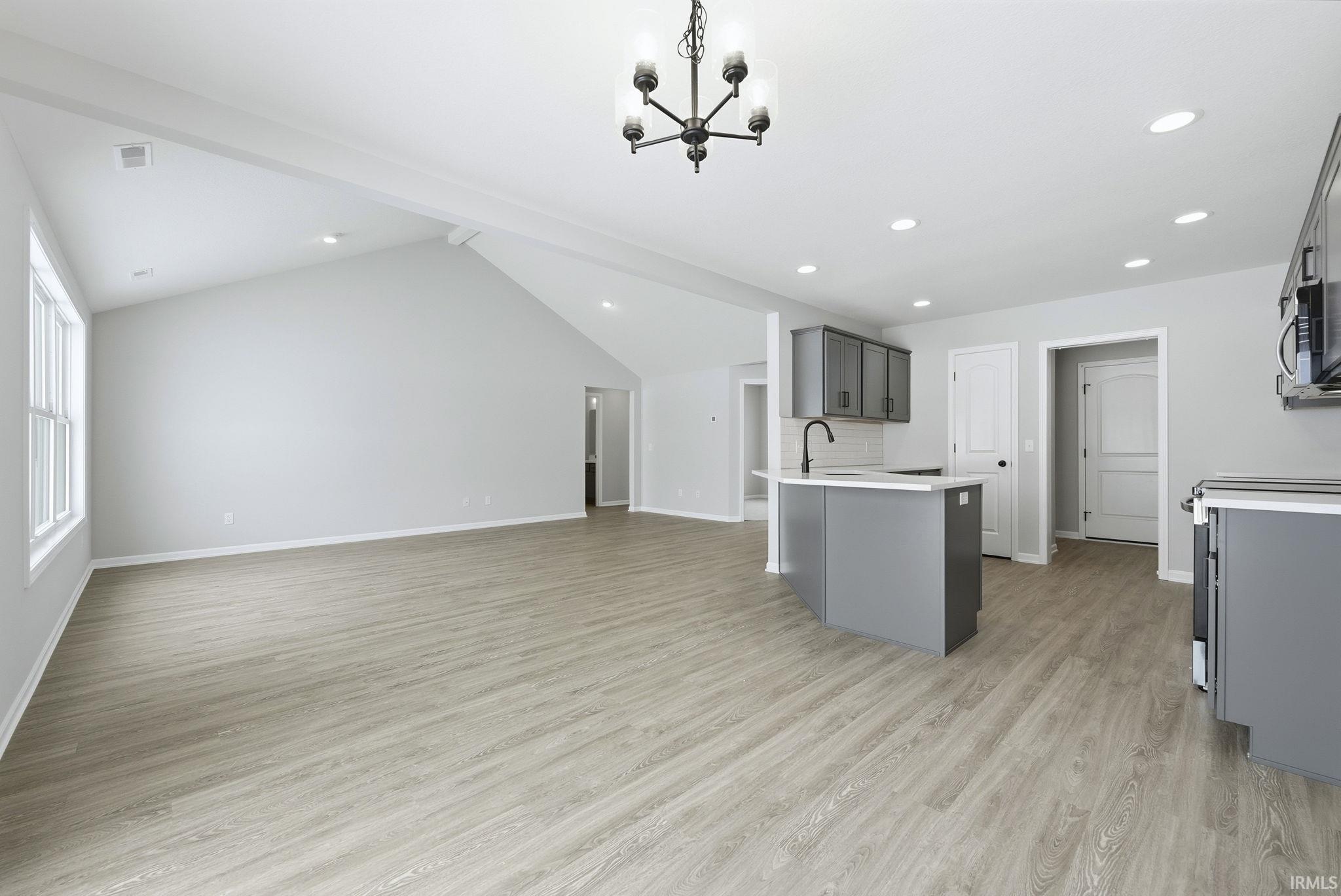 Kitchen with gray cabinets, suspended lighting, open floor plan, lofted ceiling, and a peninsula