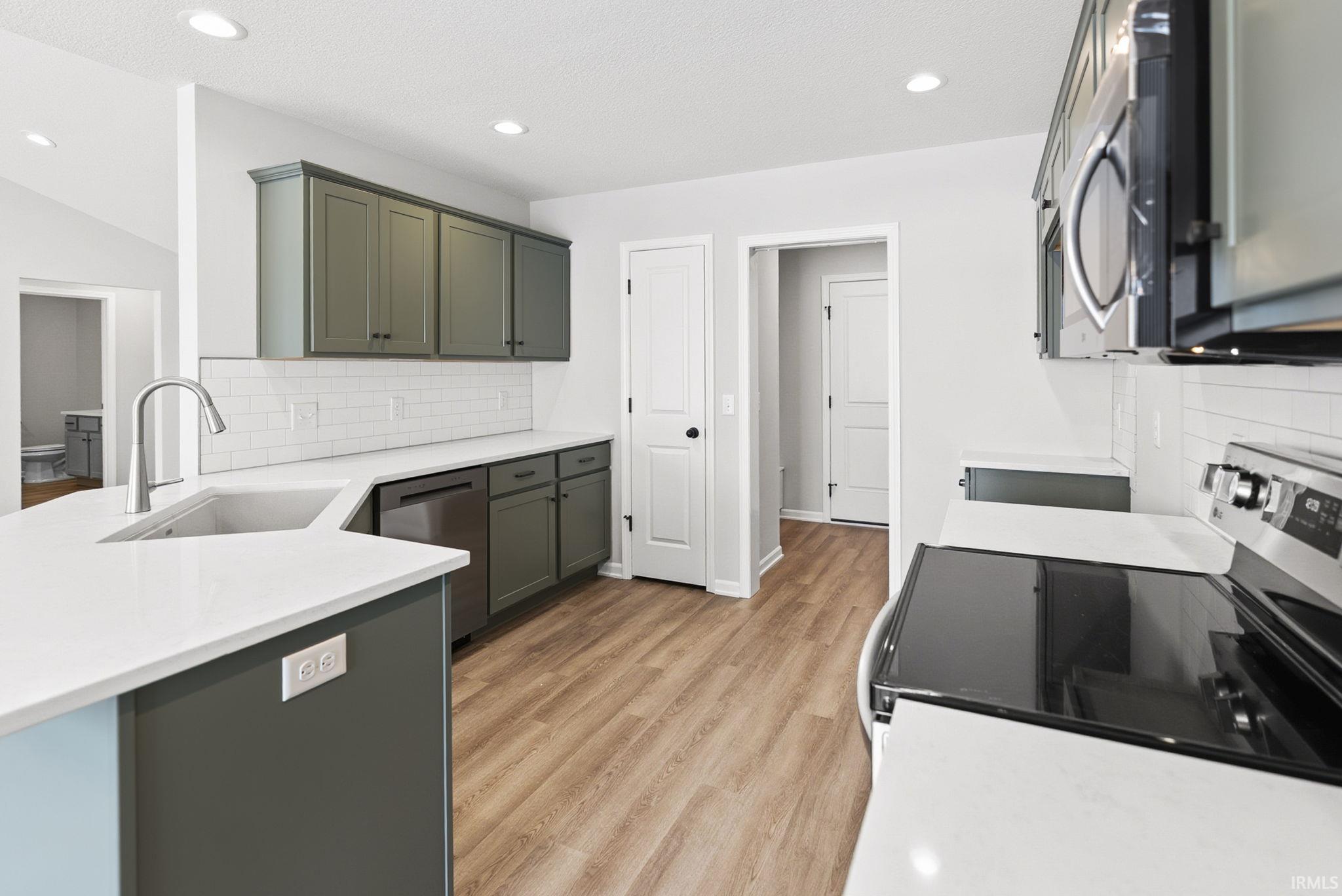 Kitchen with tasteful backsplash, stainless steel appliances, light stone countertops, a peninsula, and recessed lighting