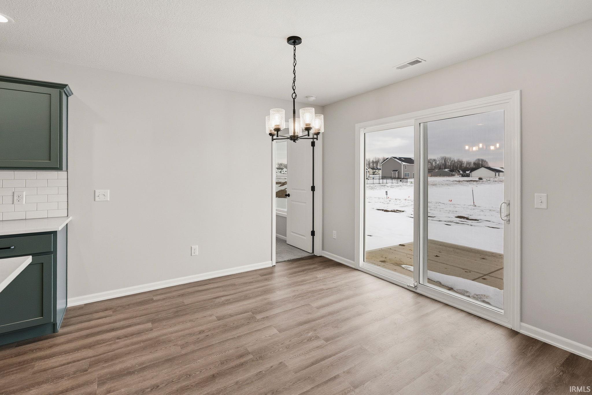 Unfurnished dining area with hanging lights and dark wood finished floors