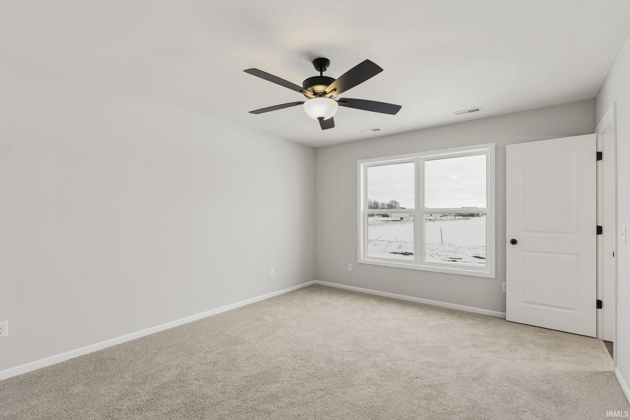 Spare room featuring light carpet and a ceiling fan