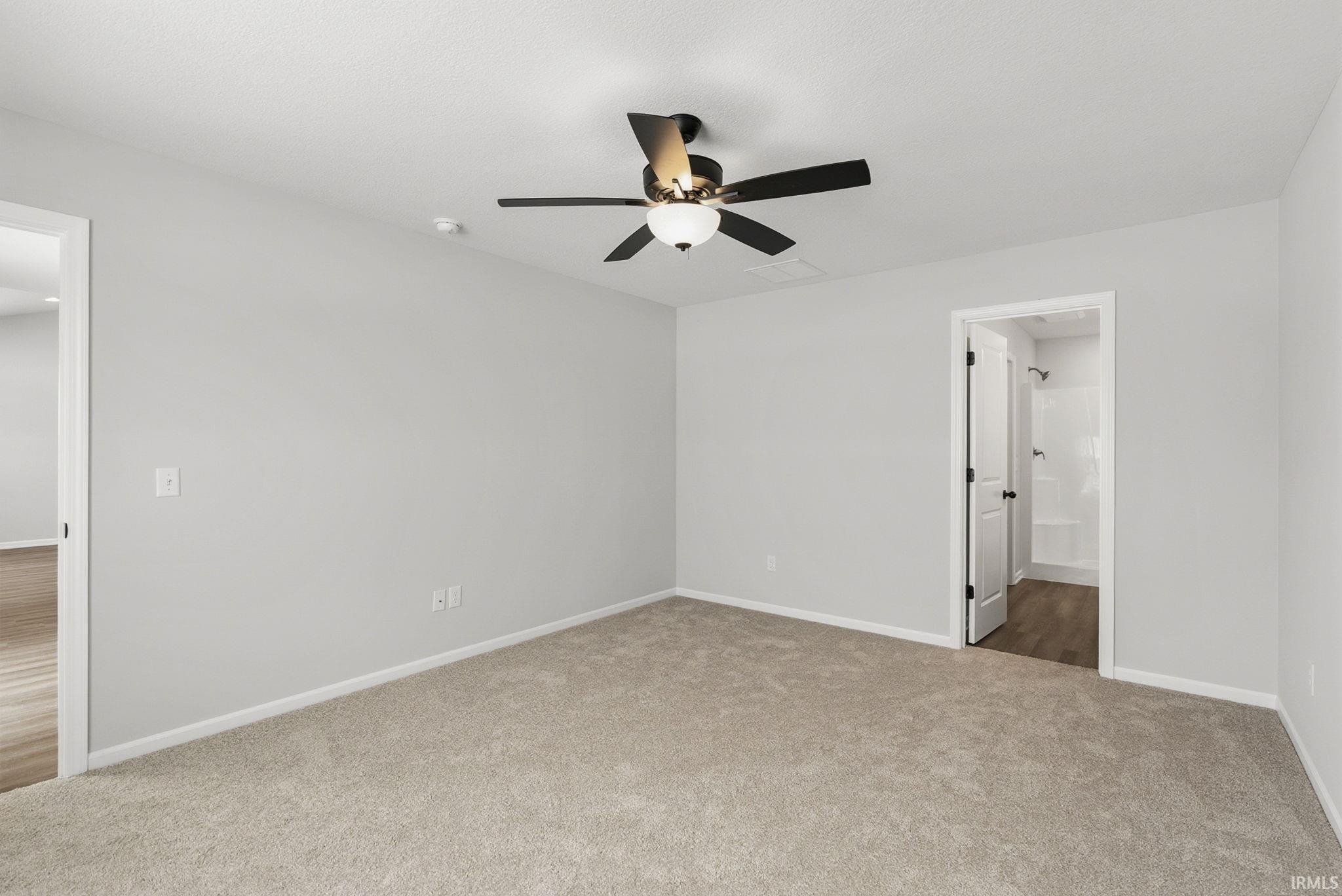 Unfurnished bedroom with light colored carpet, a ceiling fan, and ensuite bathroom
