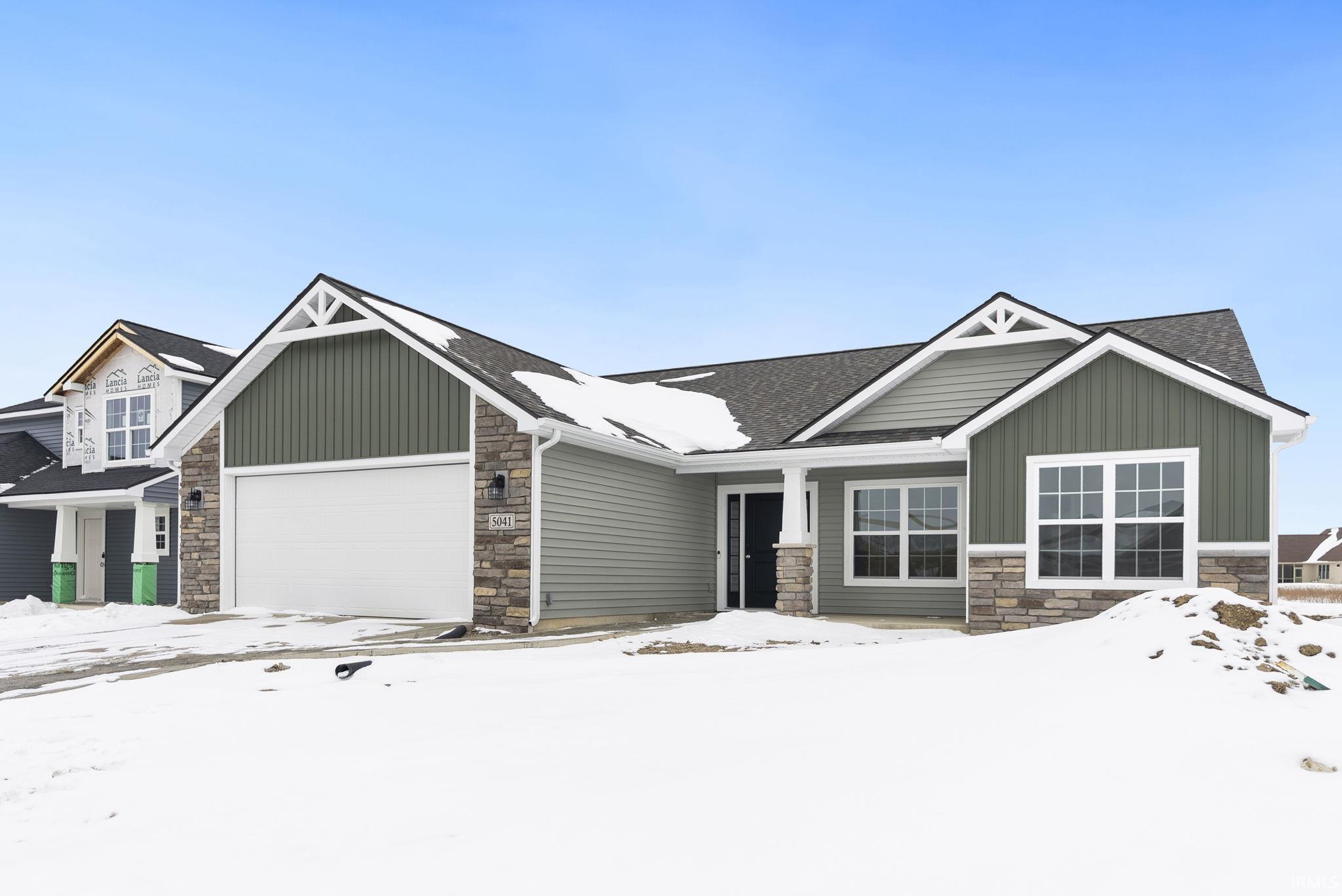 Craftsman house with stone siding, a garage, board and batten siding, and roof with shingles