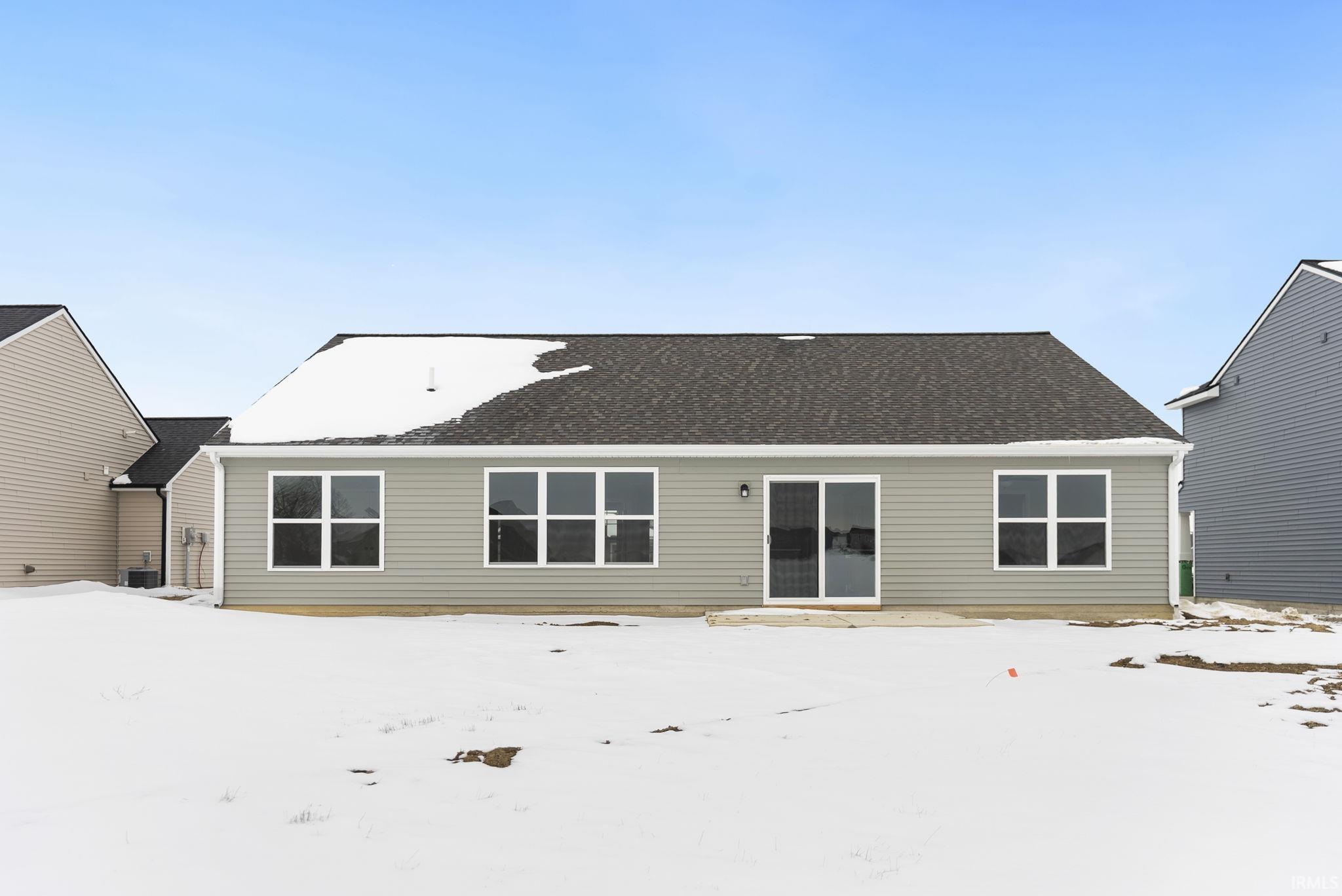 Snow covered back of property with a shingled roof