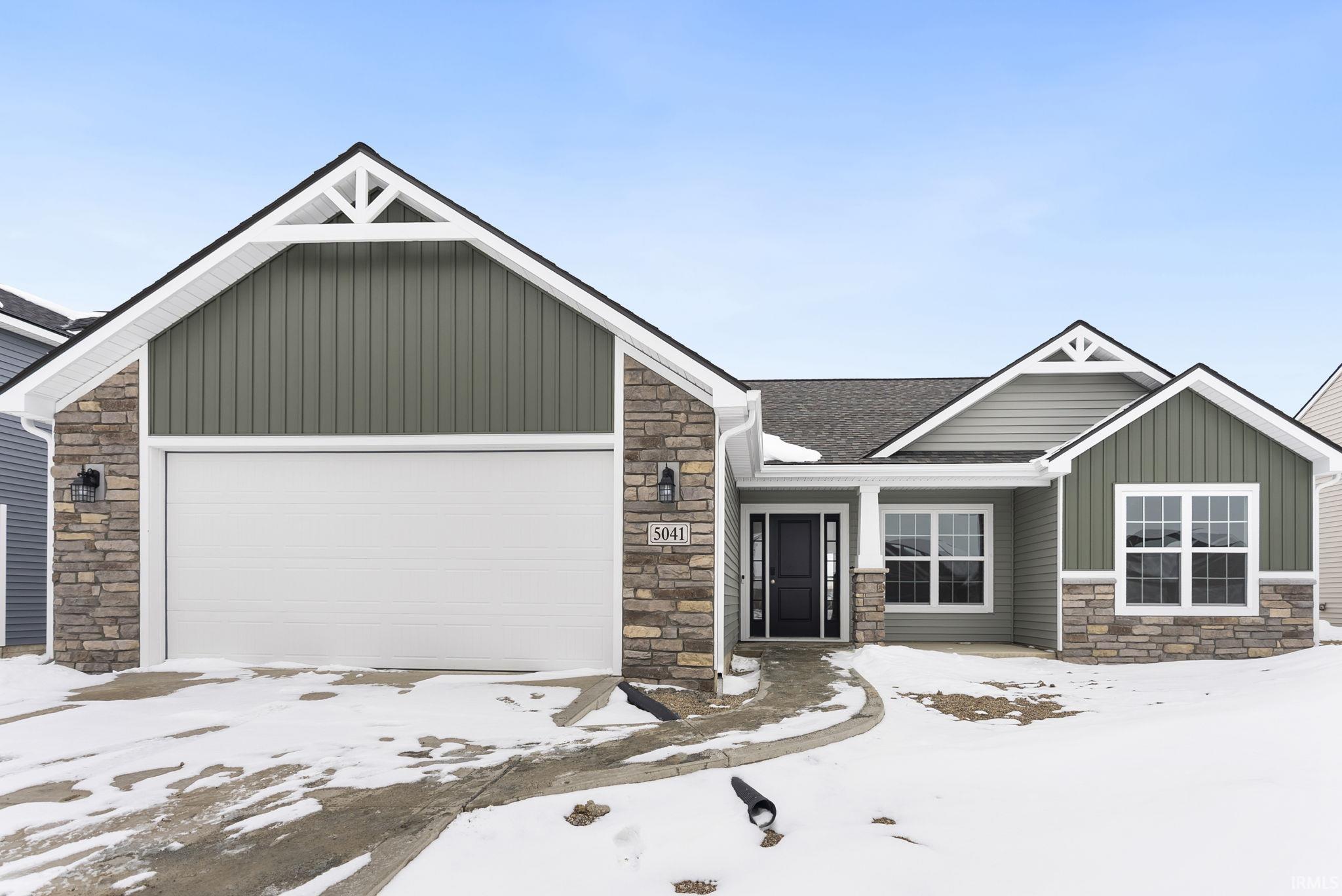 Craftsman-style home featuring stone siding, board and batten siding, a porch, and a garage