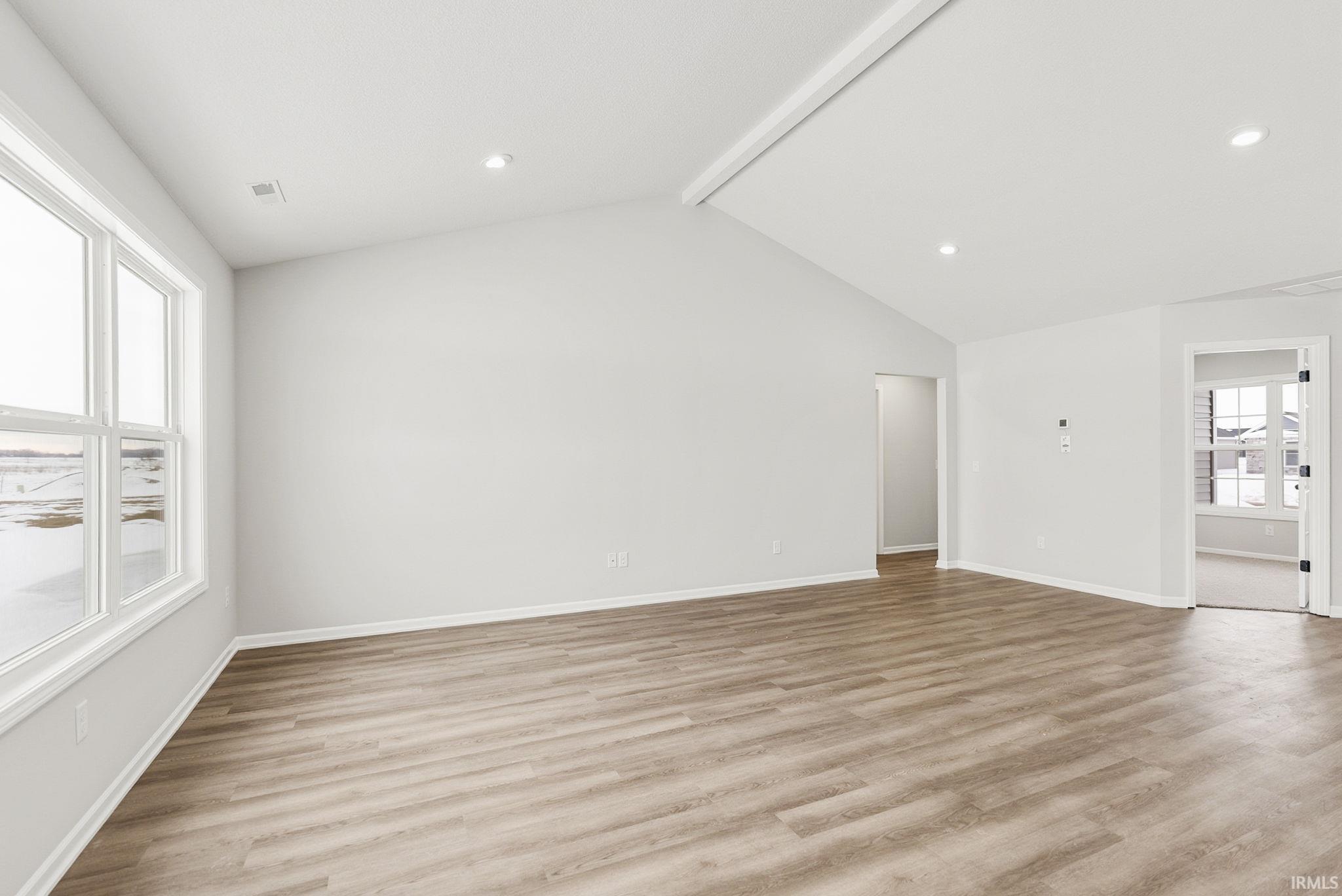 Unfurnished living room with beamed ceiling, light wood-type flooring, and recessed lighting