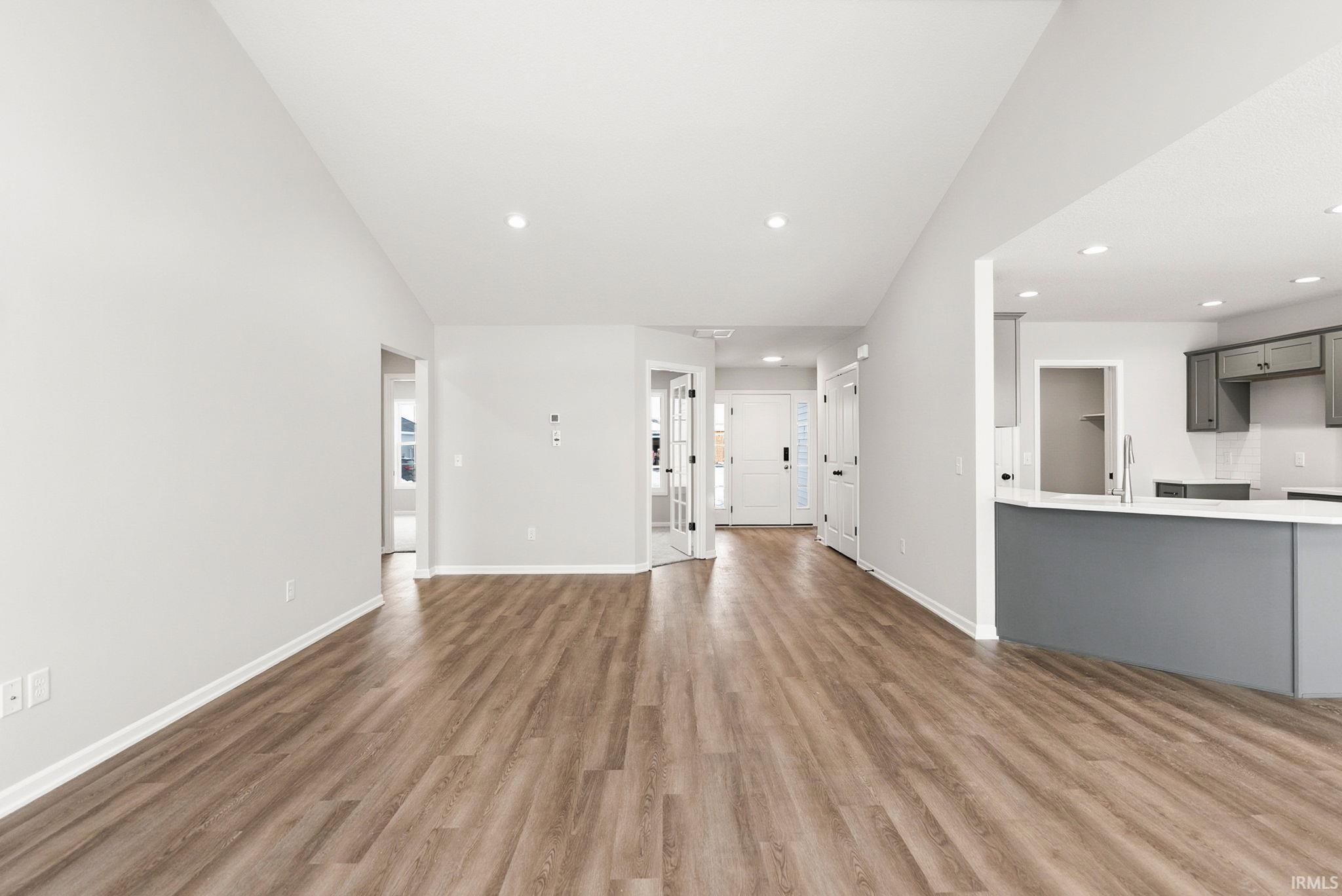 Unfurnished living room featuring vaulted ceiling, dark wood-style floors, and recessed lighting
