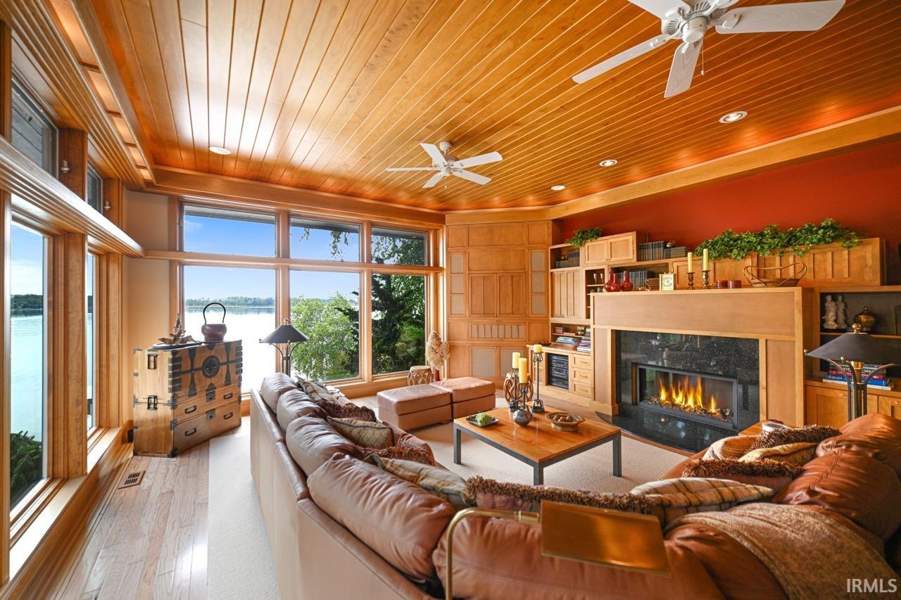 Living area featuring wooden ceiling, a water view, a high end fireplace, a ceiling fan, and light wood-style flooring