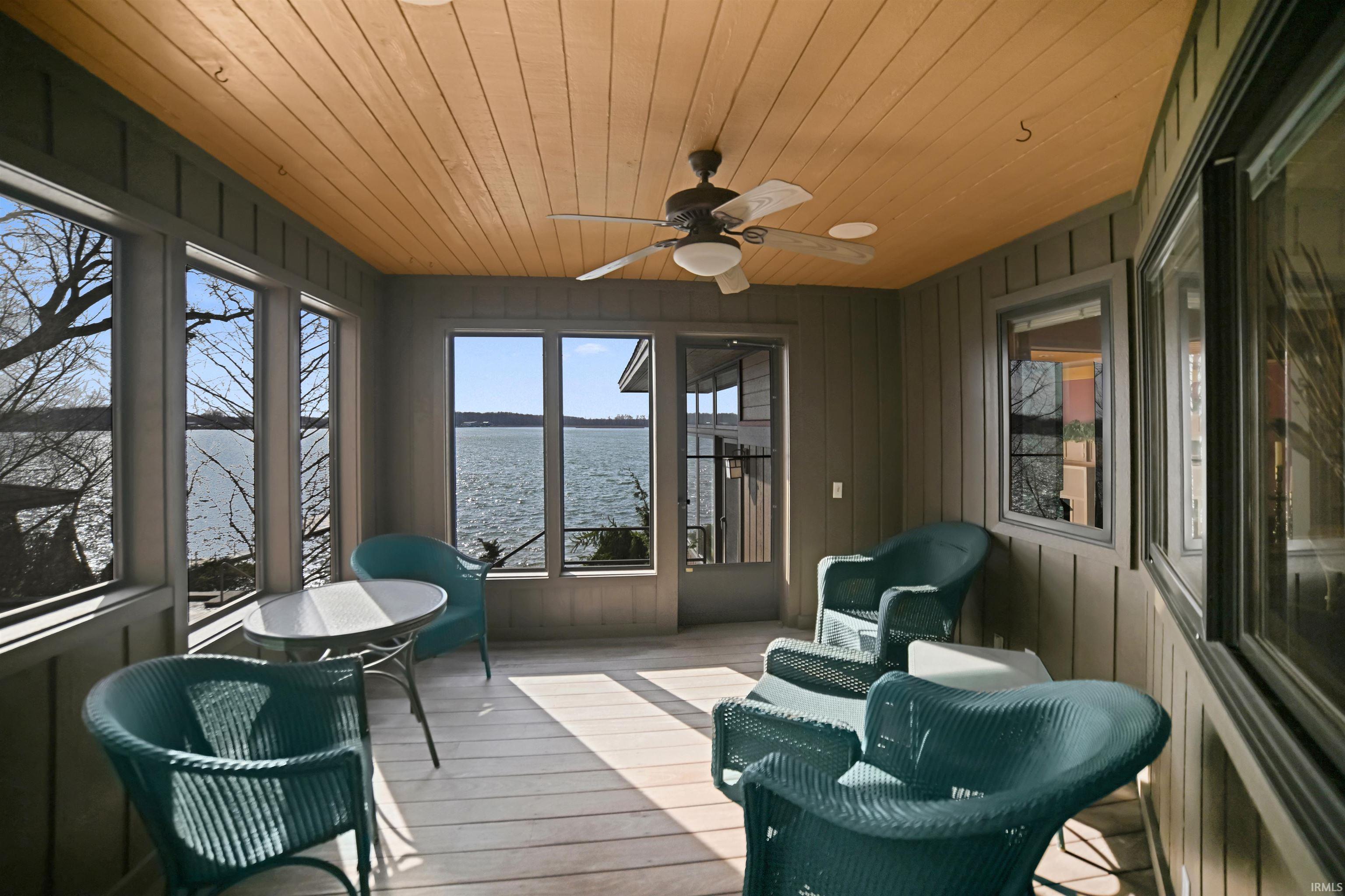 Sunroom / solarium featuring a ceiling fan and a water view