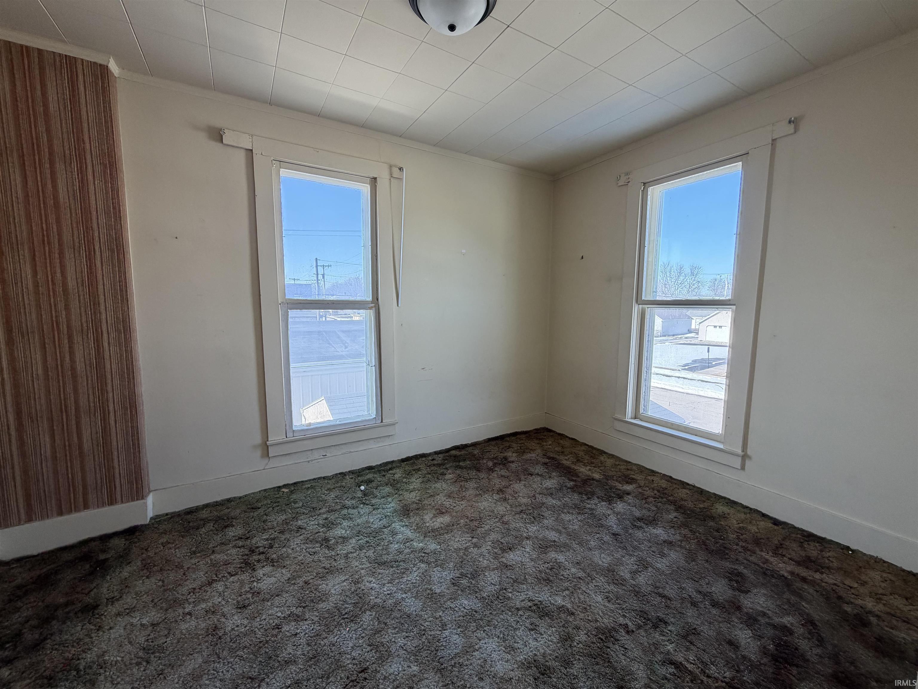 Spare room featuring dark colored carpet and crown molding