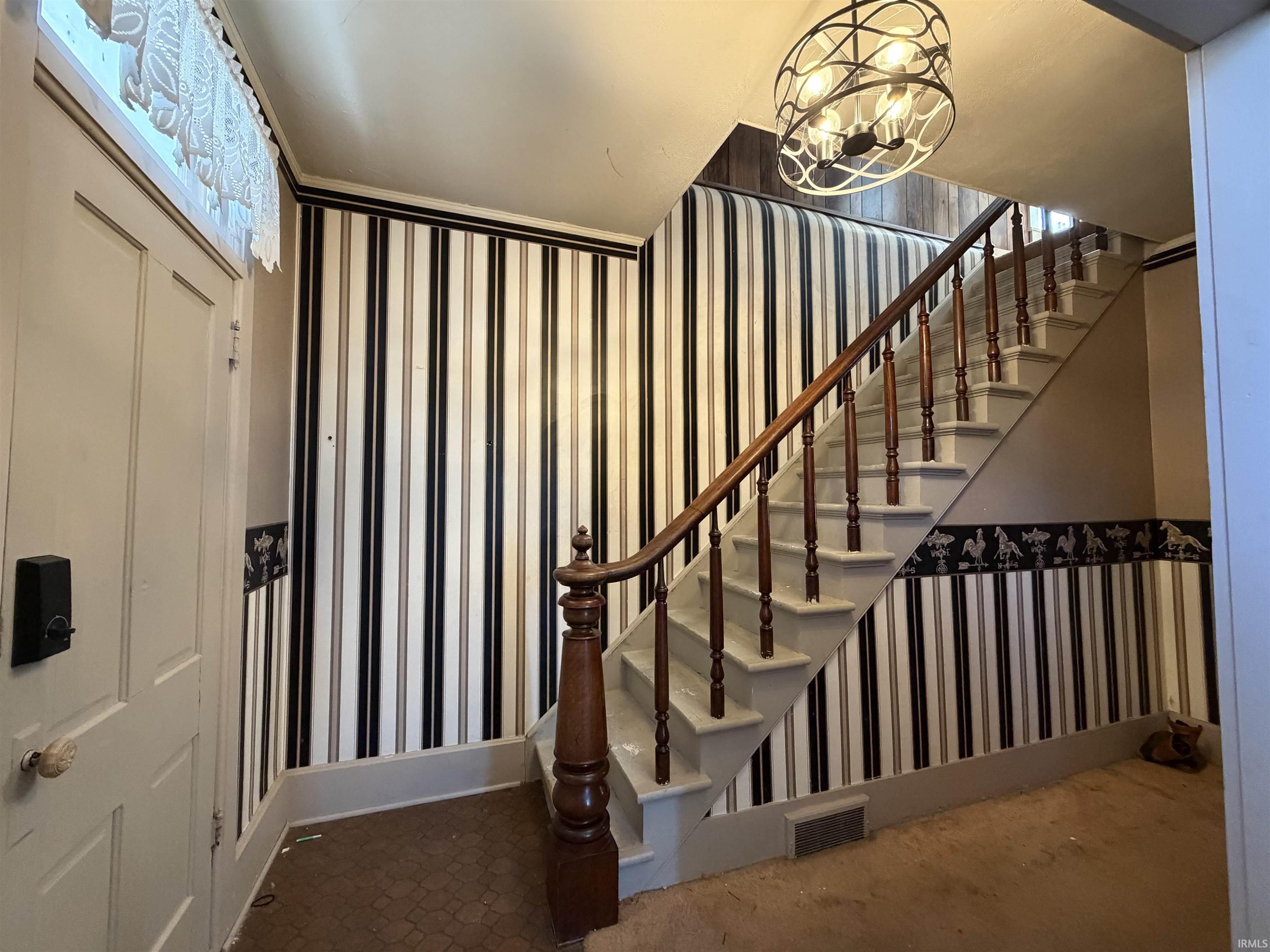 Staircase with wallpapered walls and hanging lights