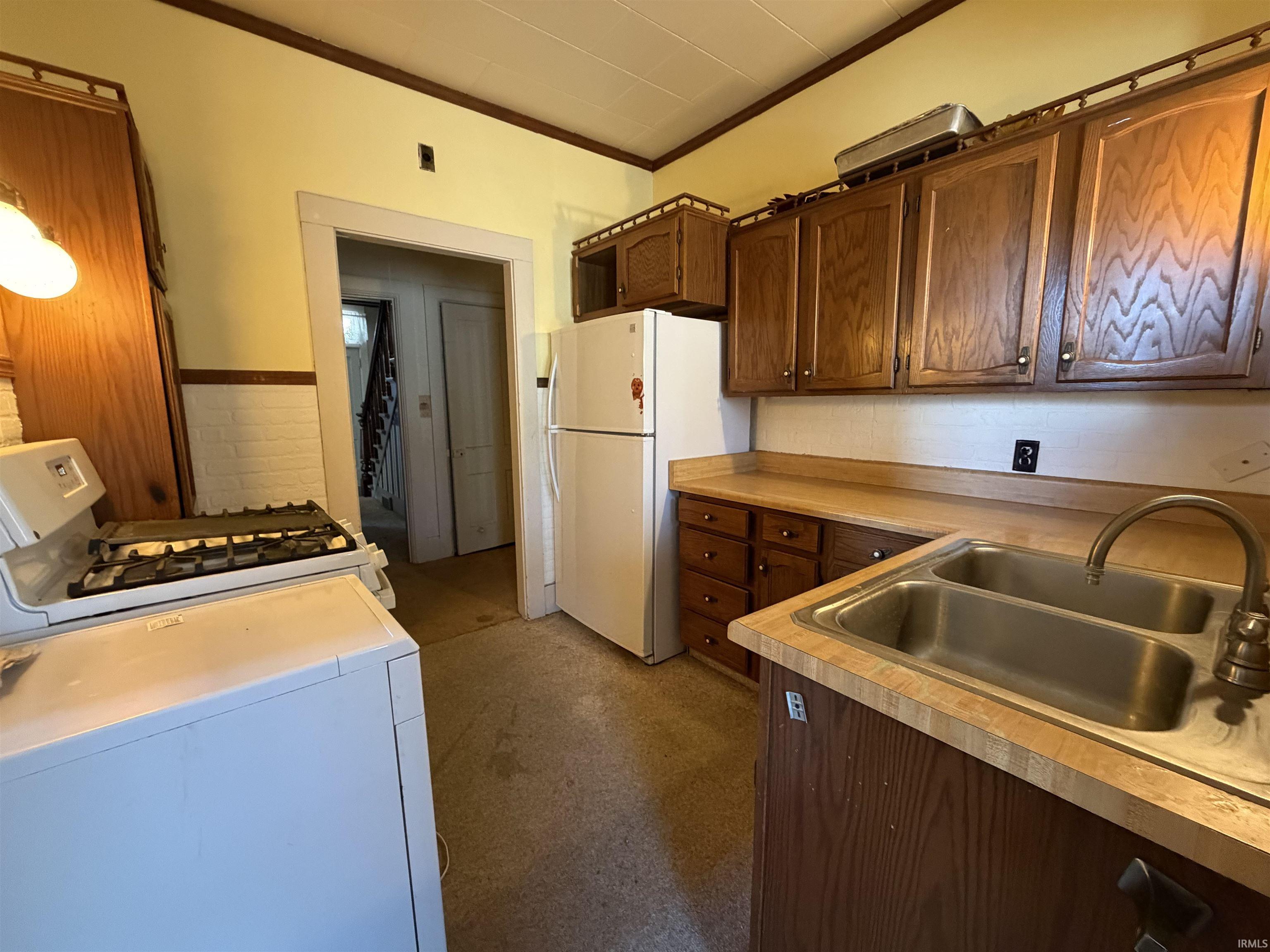 Kitchen with crown molding, white appliances, light countertops, and washer / clothes dryer