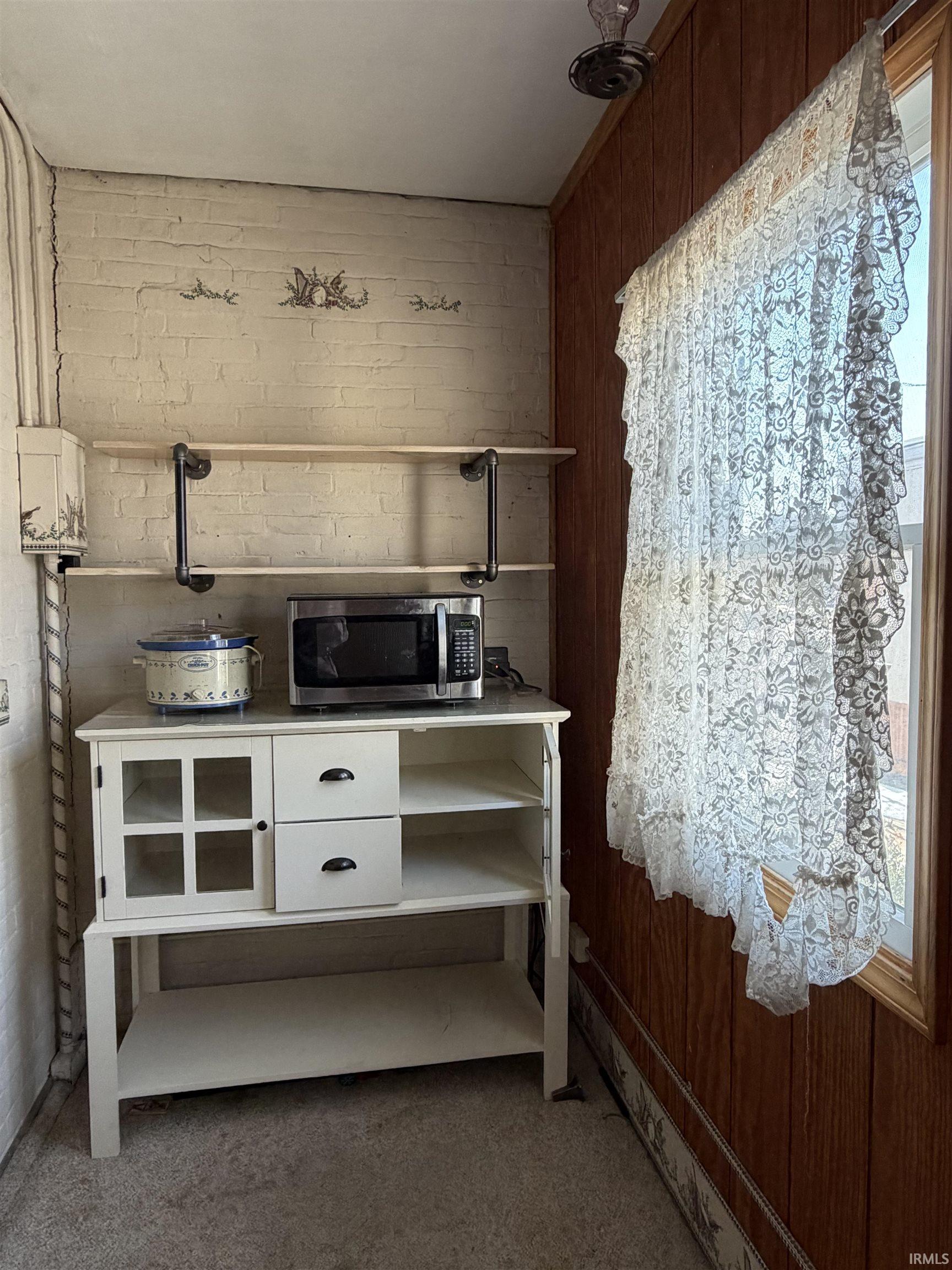 Bar featuring white cabinets, stainless steel microwave, and carpet flooring