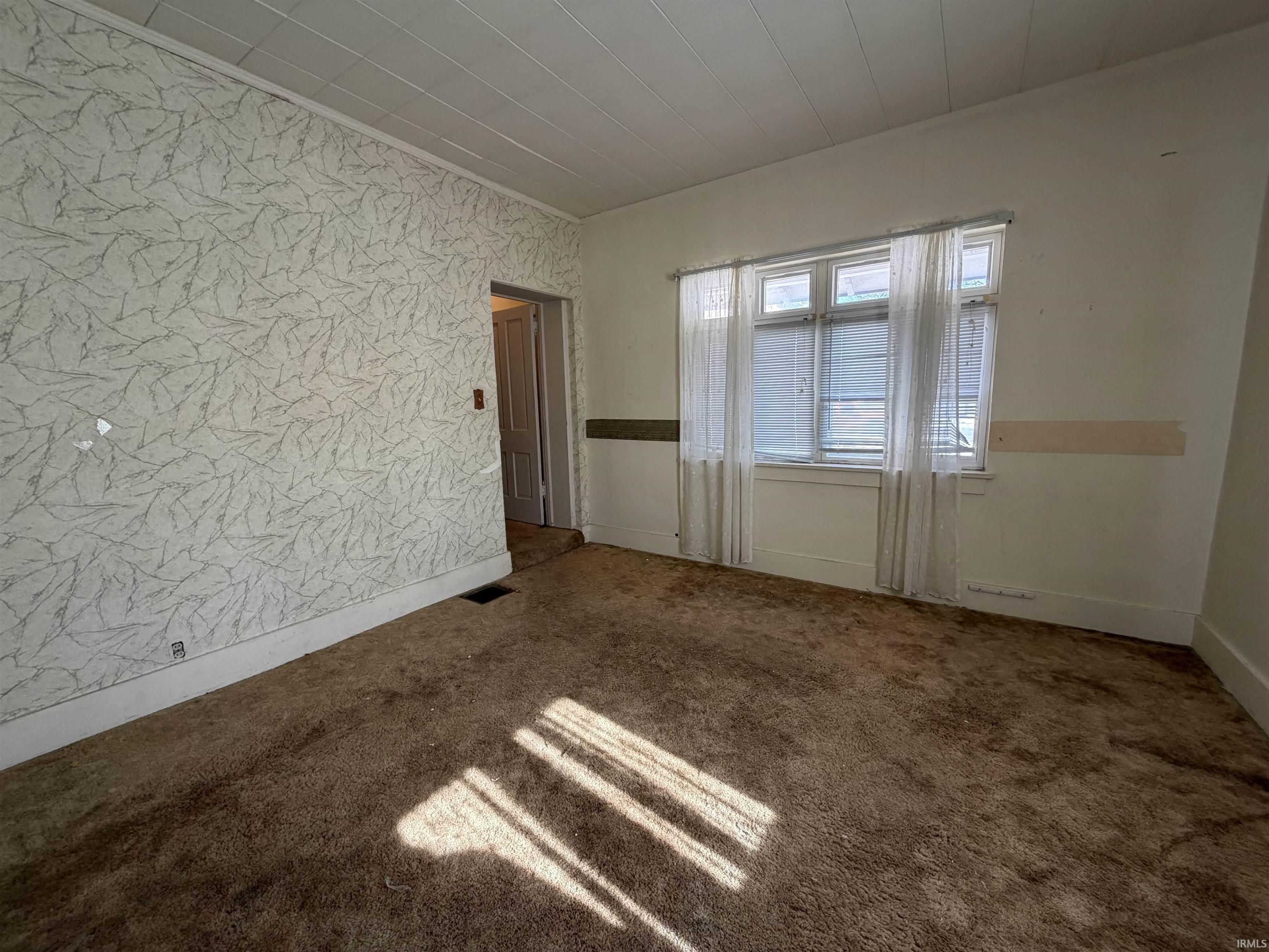 Spare room featuring carpet and wallpapered walls