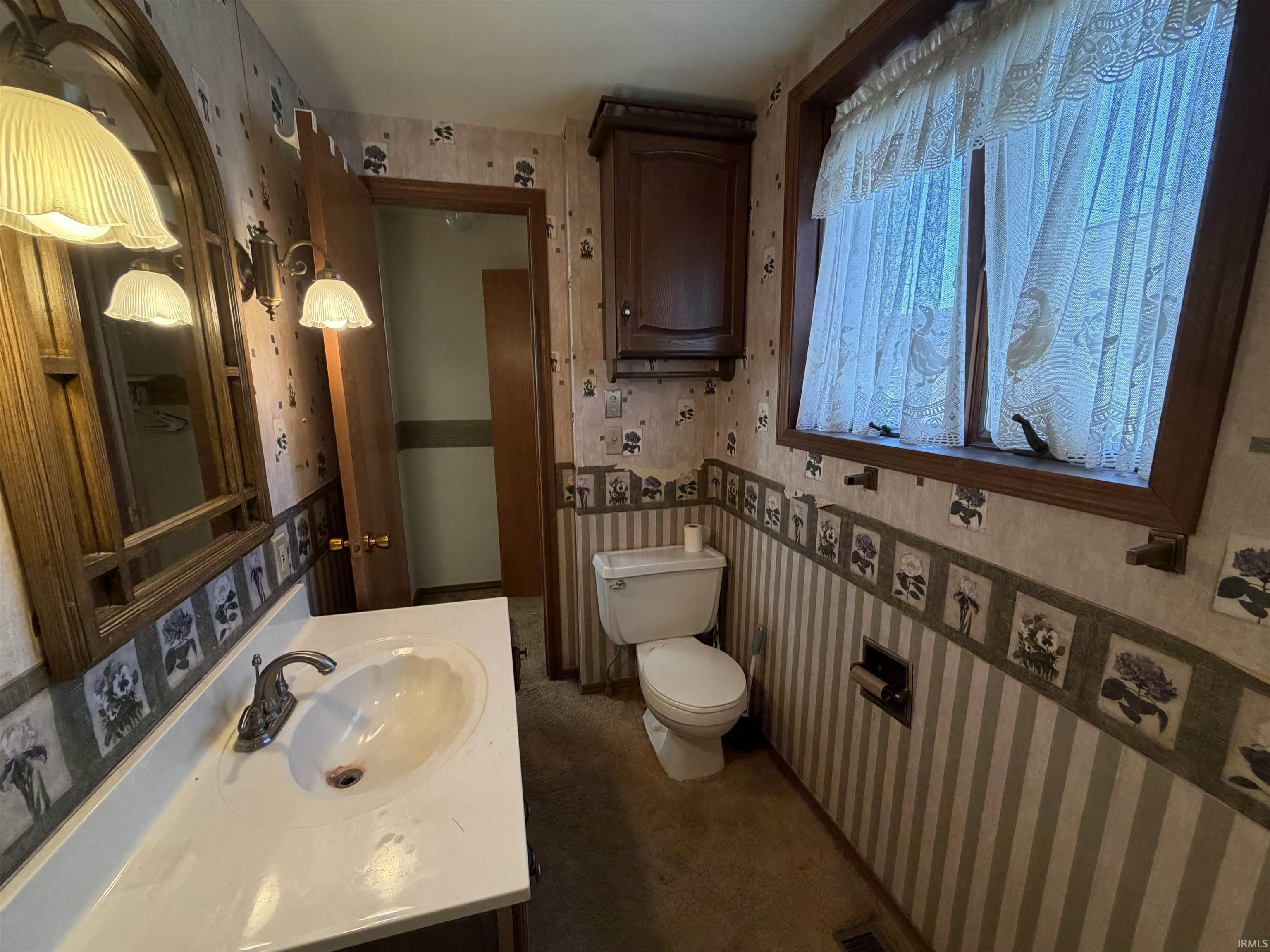 Bathroom featuring wallpapered walls and vanity