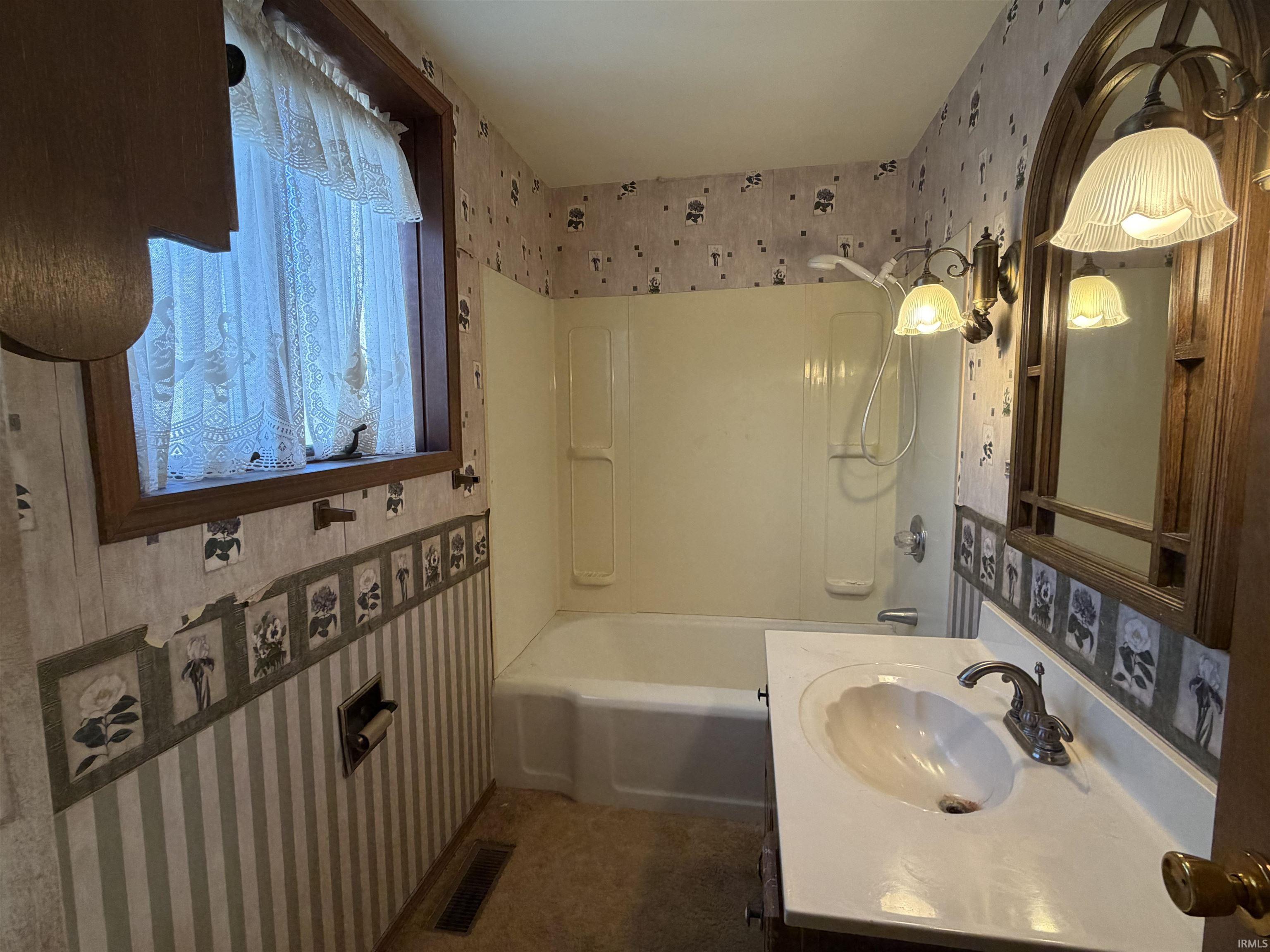 Bathroom featuring wallpapered walls, bathtub / shower combination, and vanity