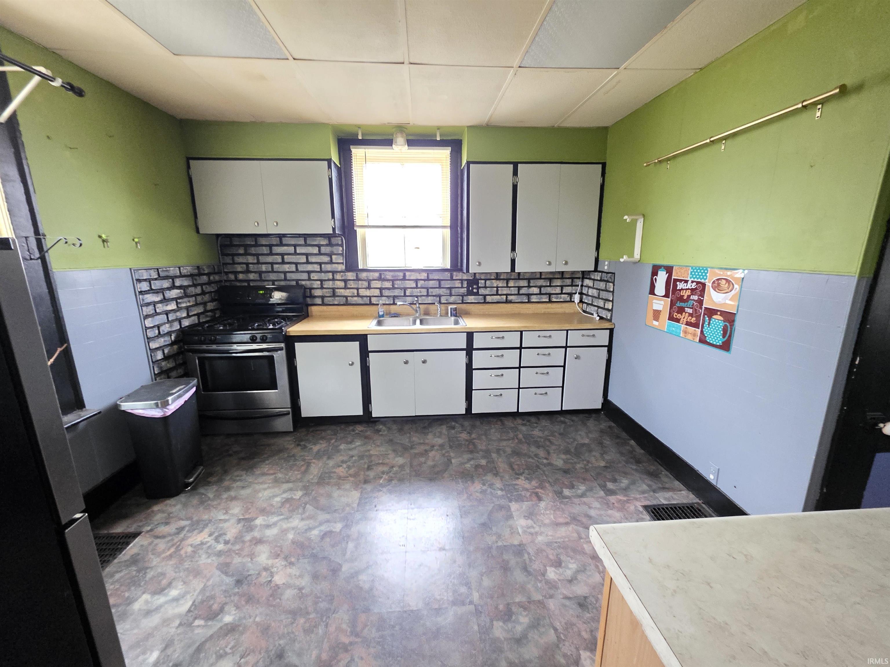 Kitchen with light countertops, stainless steel appliances, decorative backsplash, and white cabinets
