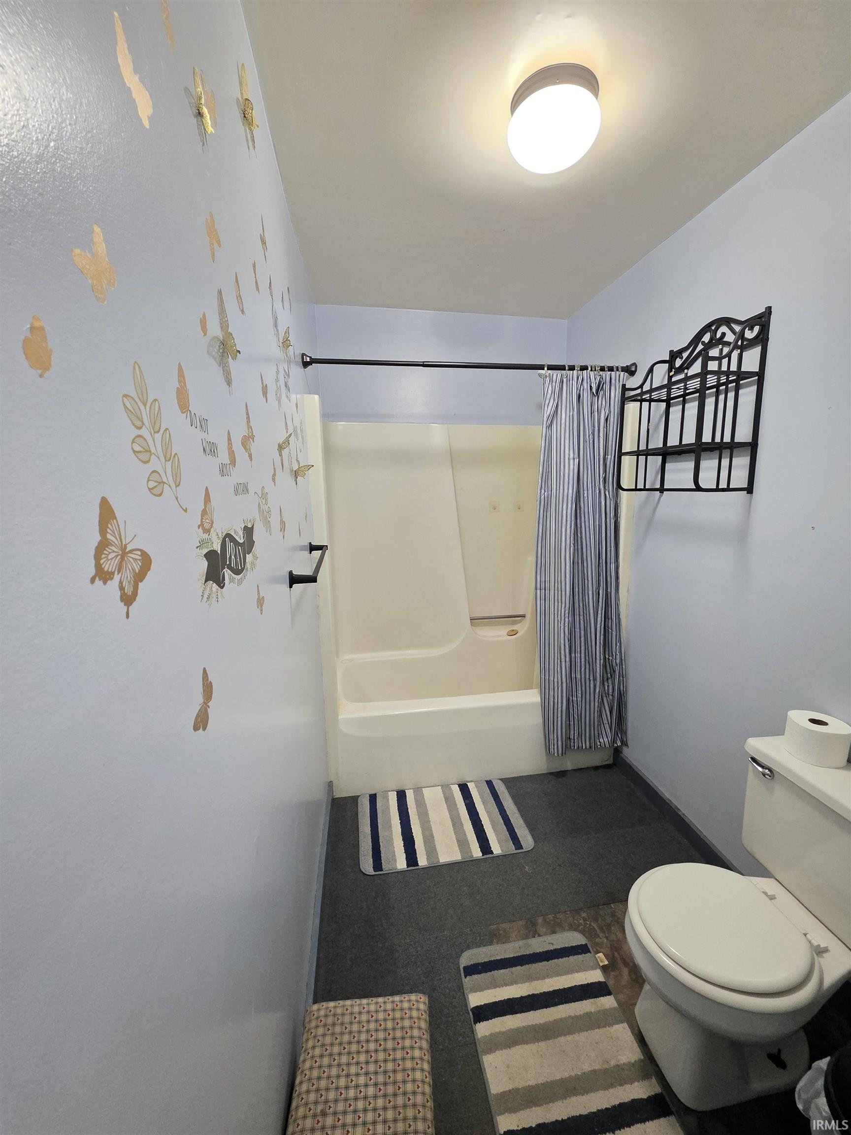 Bathroom with shower / bath combination with curtain and toilet