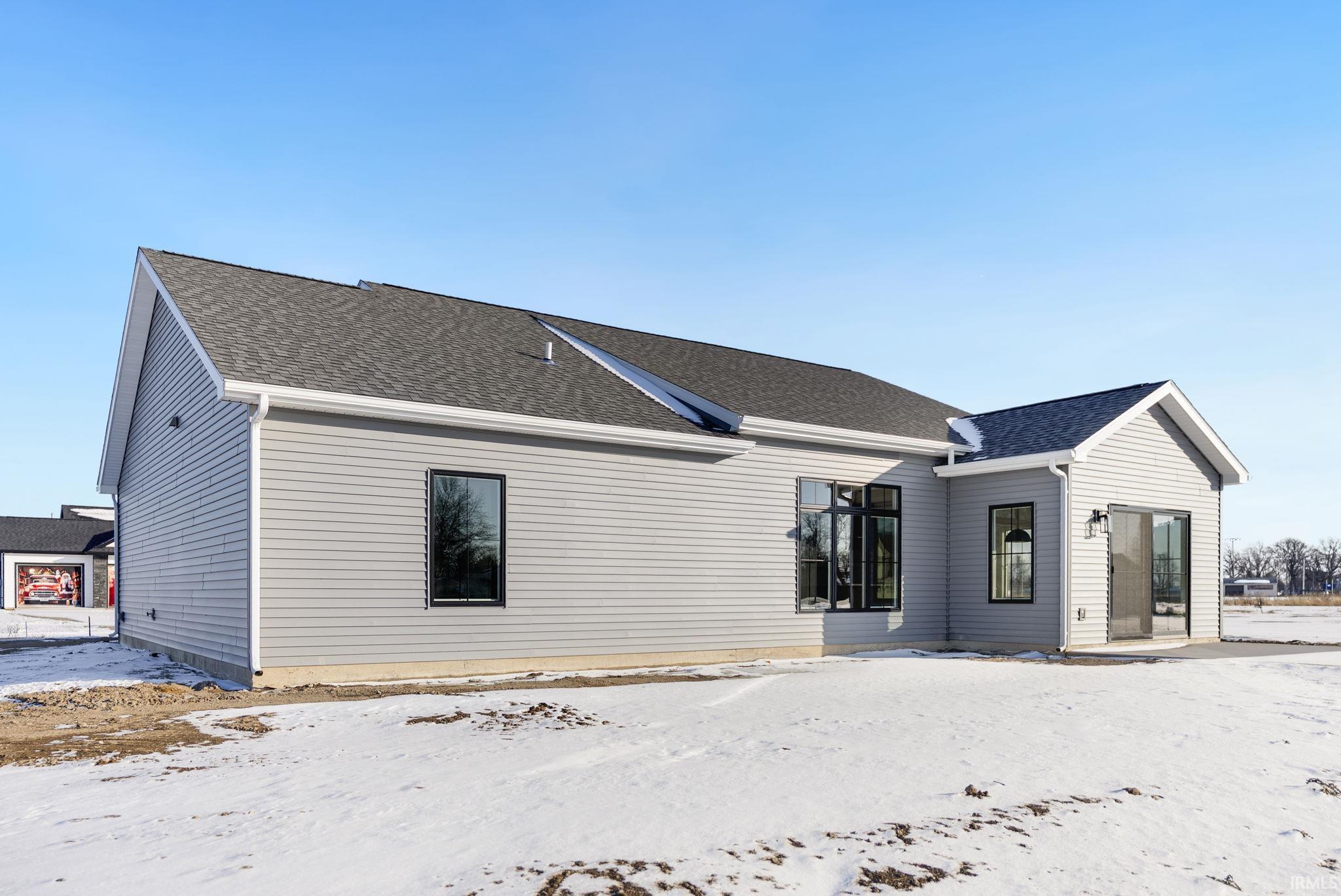 Snow covered house featuring a shingled roof