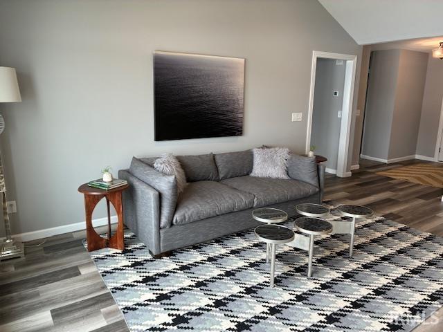 Living room featuring dark wood finished floors and vaulted ceiling
