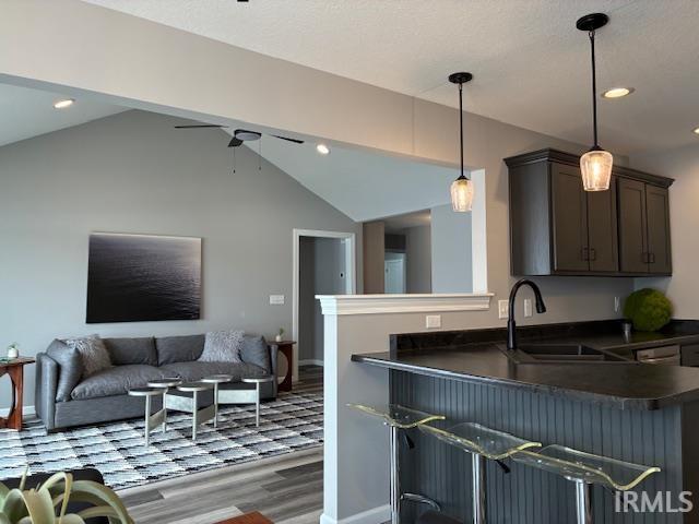 Kitchen featuring dark countertops, a peninsula, dark wood-type flooring, hanging light fixtures, and recessed lighting