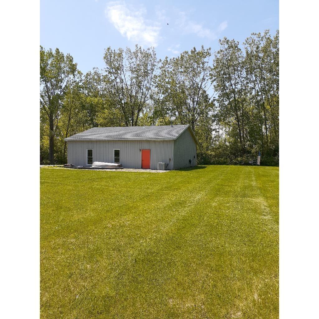 Back of house with a yard, a pole building, and an outbuilding