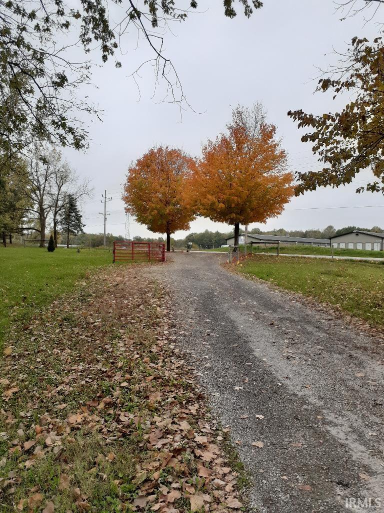 View of dirt / gravel driveway featuring a rural view and a gated entry