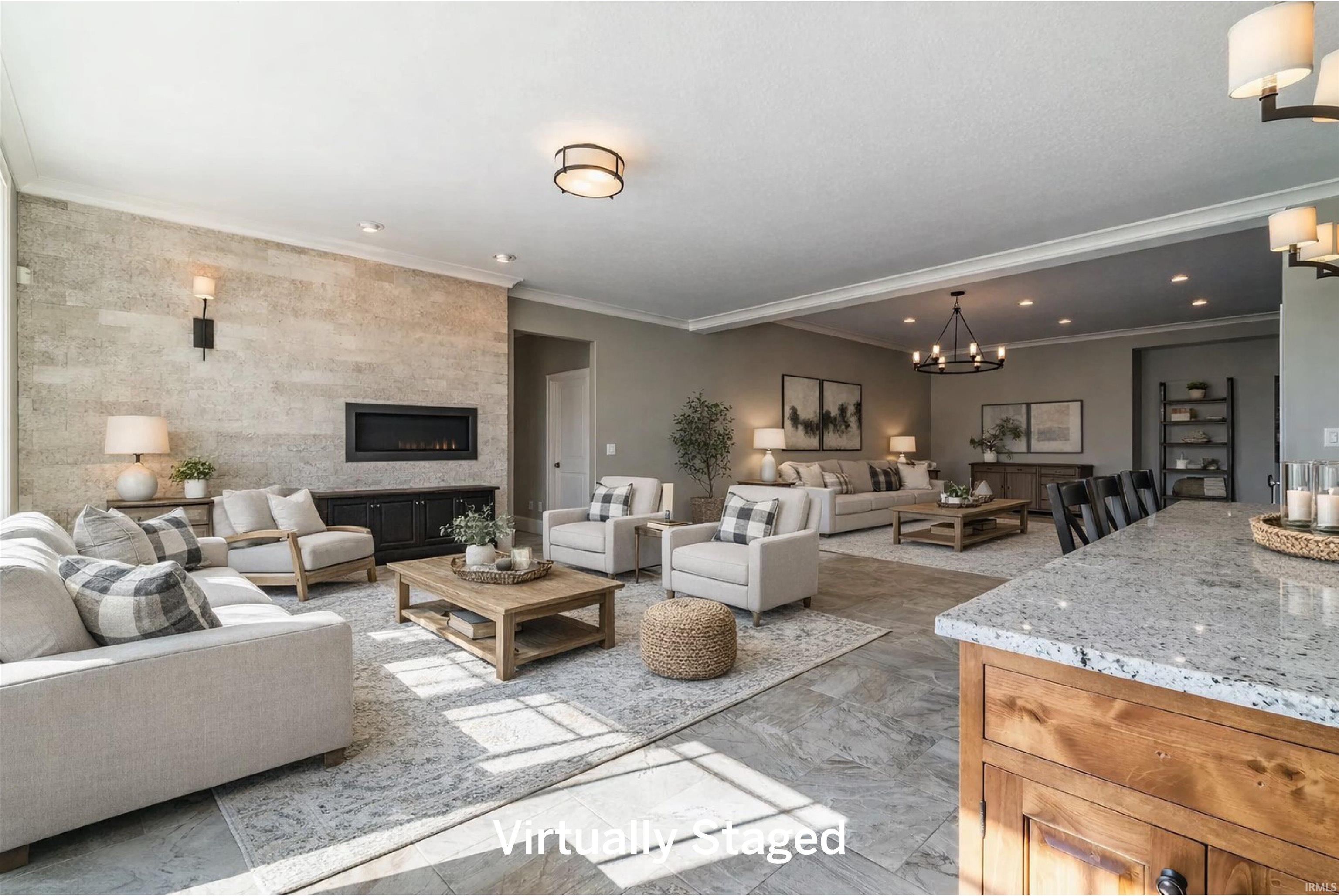 Living area with crown molding, a large fireplace, and a chandelier