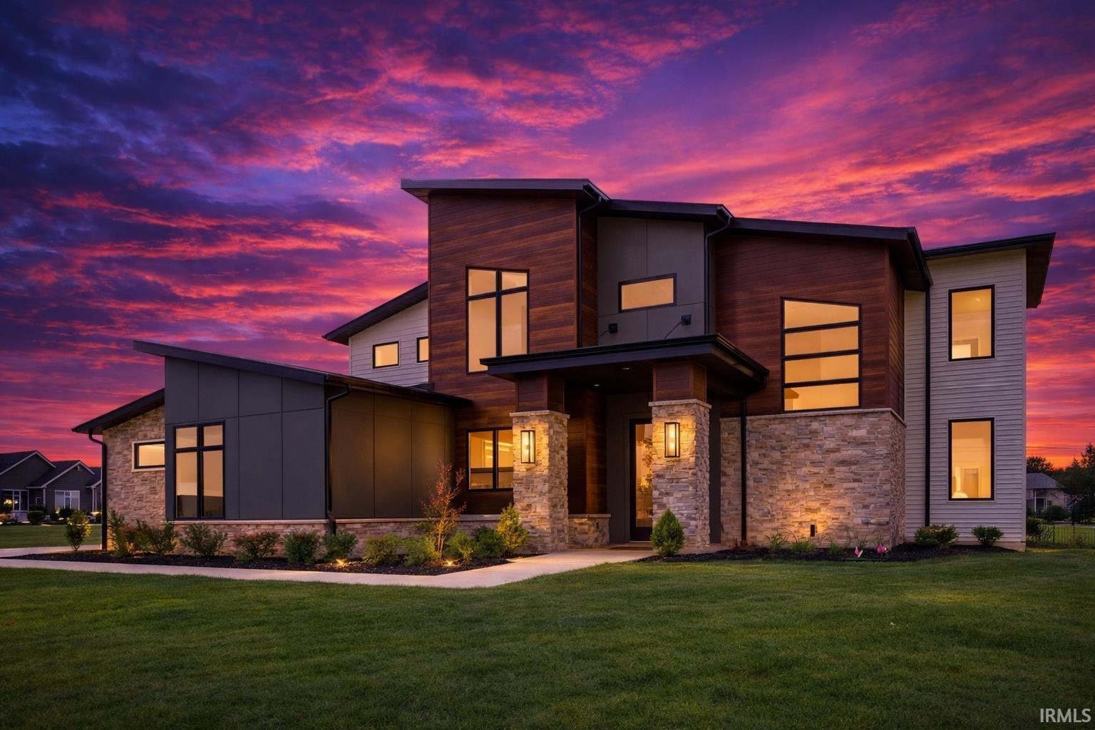 Modern home featuring stone siding, a yard, and board and batten siding