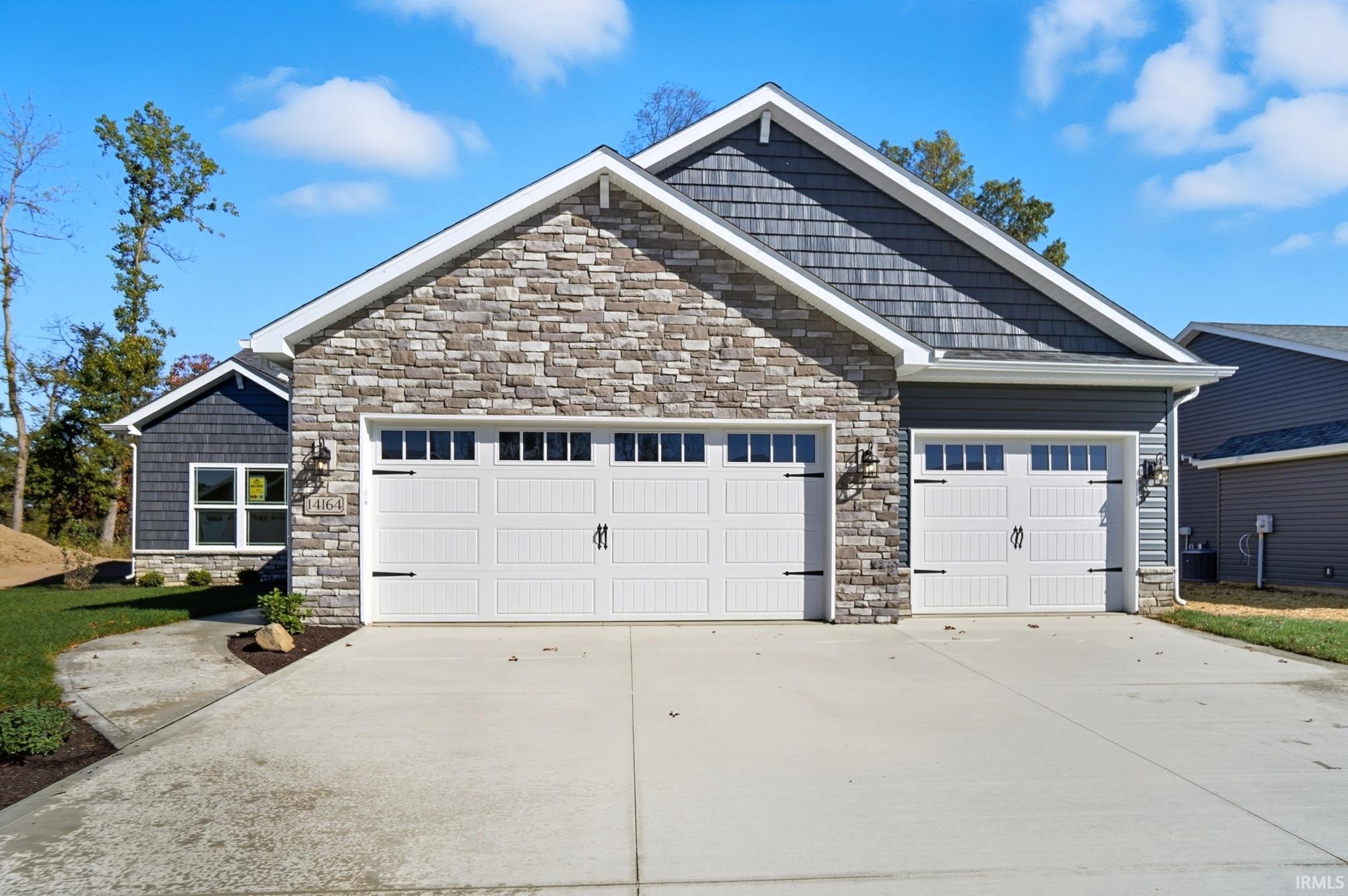 Craftsman-style house featuring stone siding, concrete driveway, and a garage