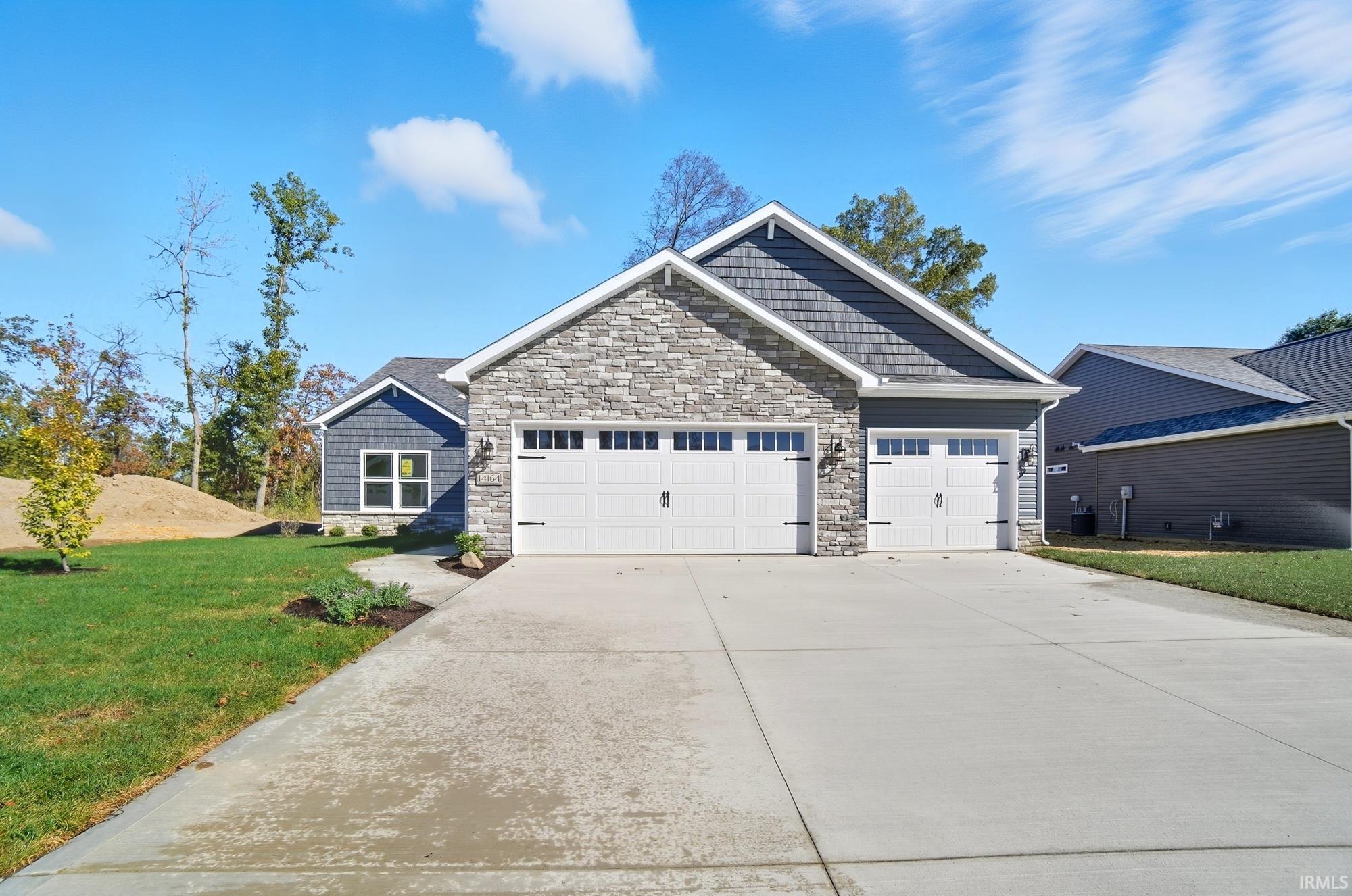Craftsman house with stone siding, a front yard, concrete driveway, and a garage