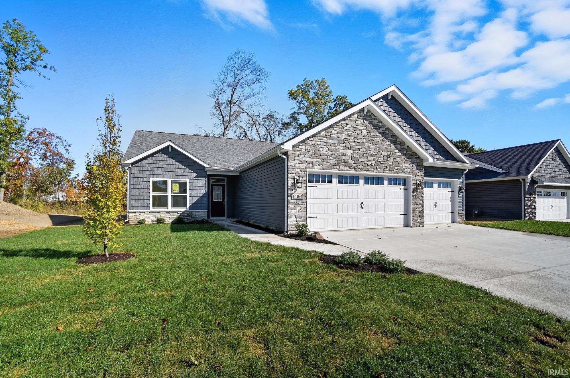 Craftsman house with stone siding, an attached garage, concrete driveway, a front lawn, and roof with shingles