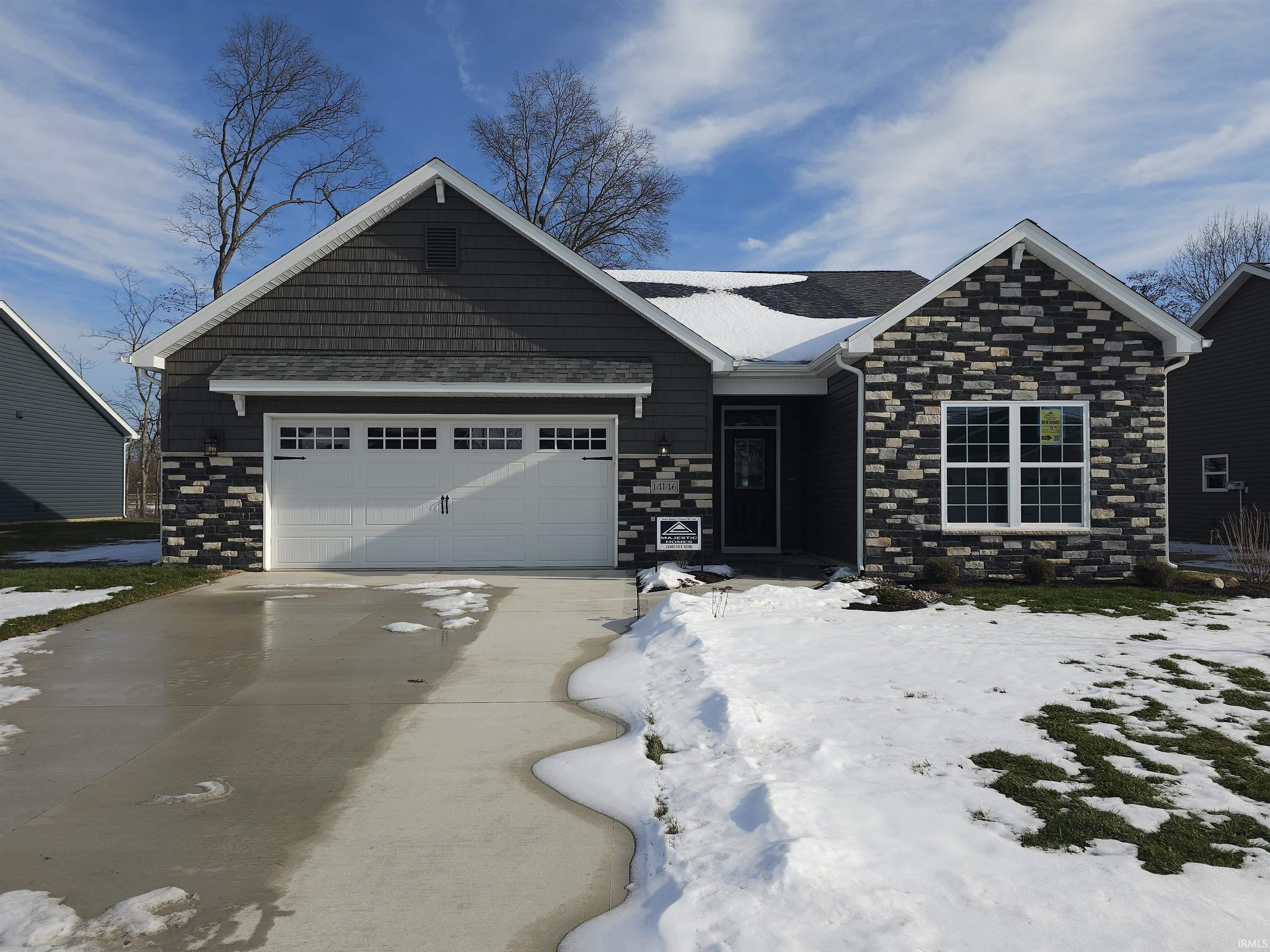 View of front of property featuring stone siding, concrete driveway, and a garage